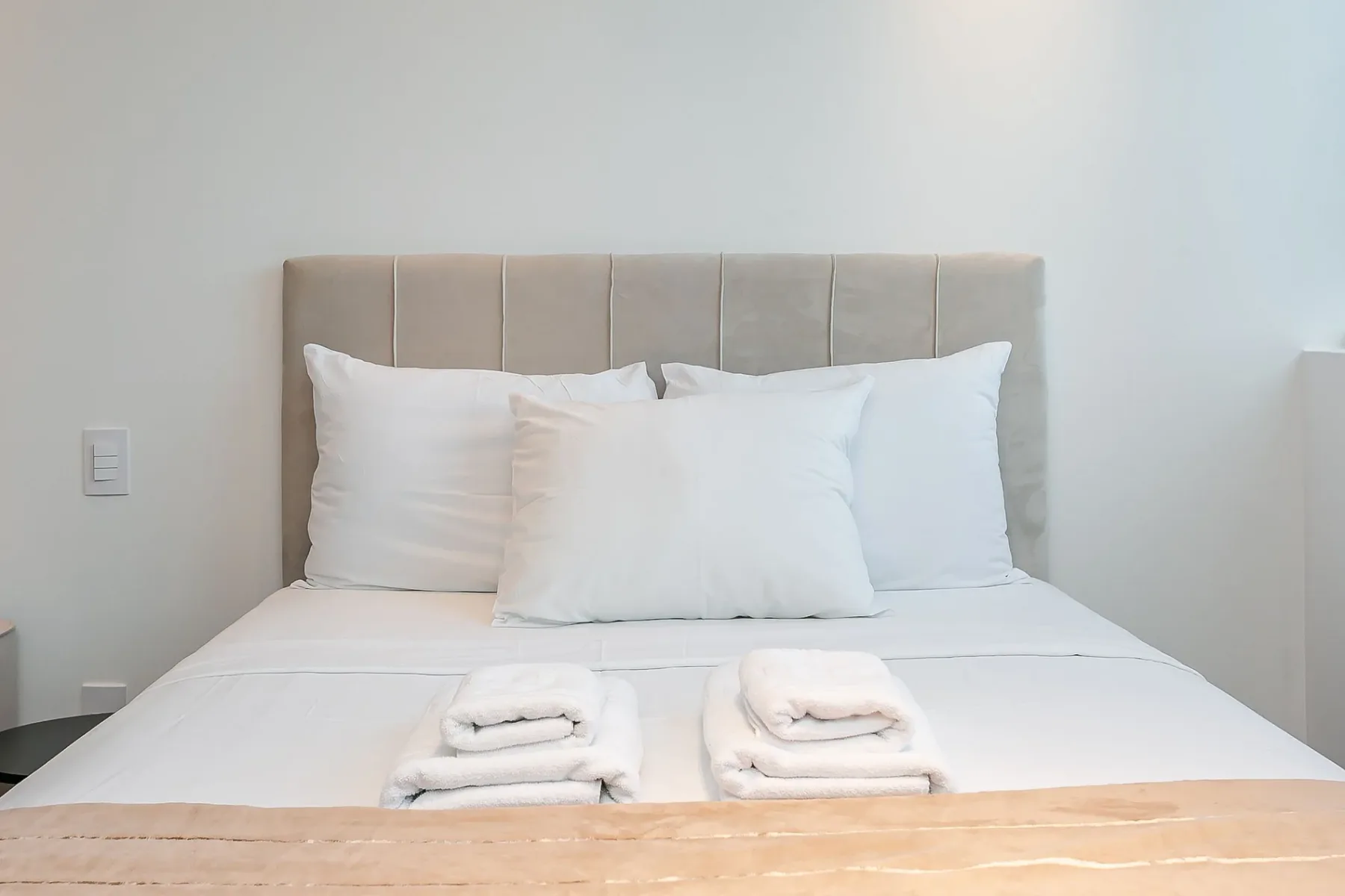 A neatly made bed with white pillows and folded towels.