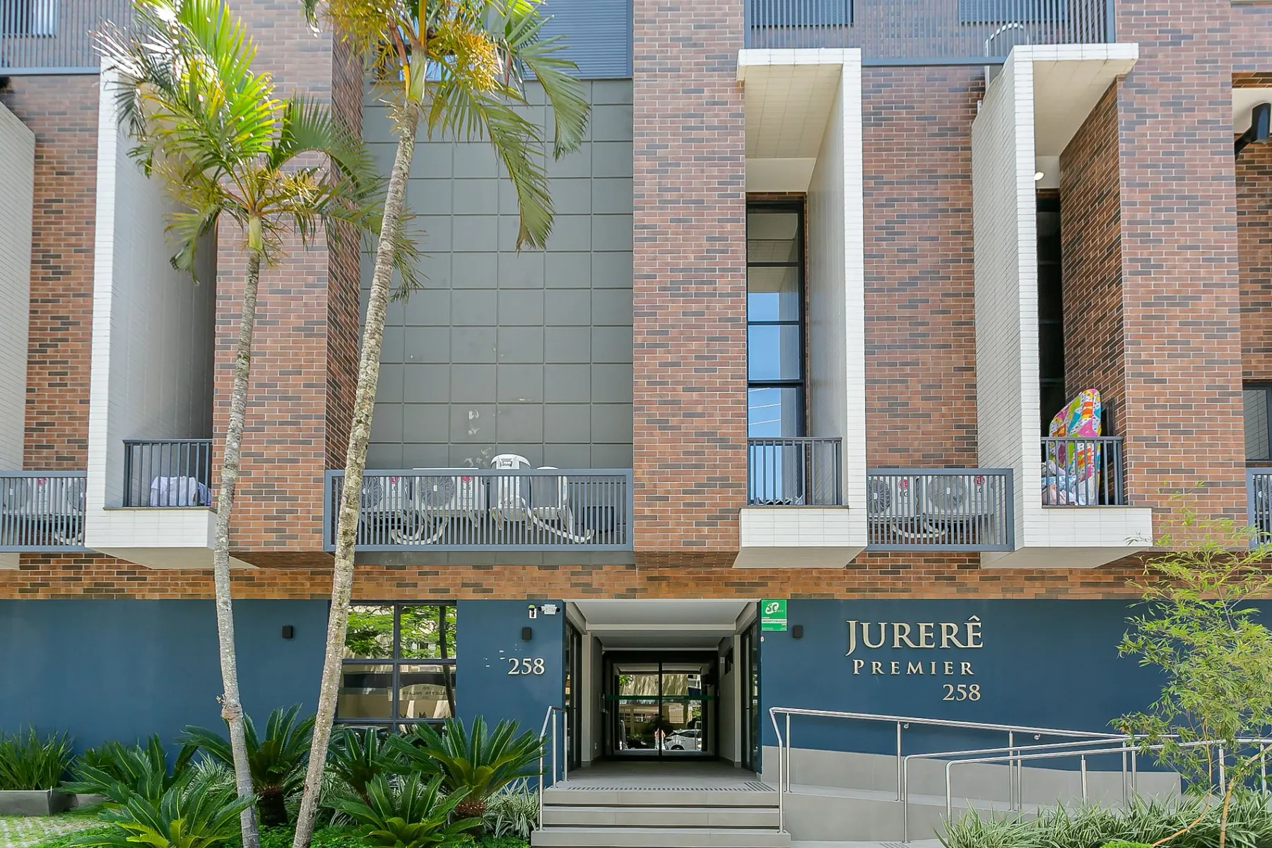 Shared amenity: Brick apartment building with a glass-fronted entrance and palm trees.