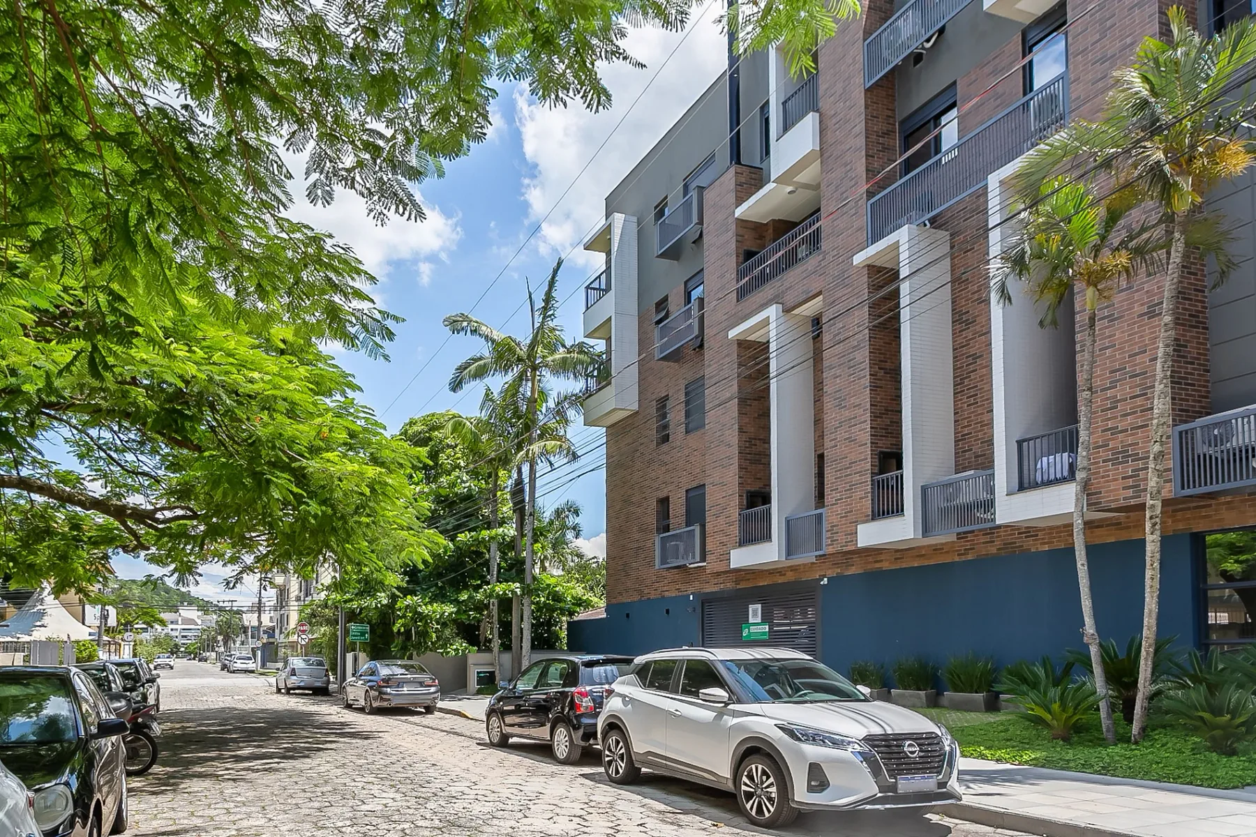Shared amenity: A brick apartment building stands along a tree-lined street with parked cars.