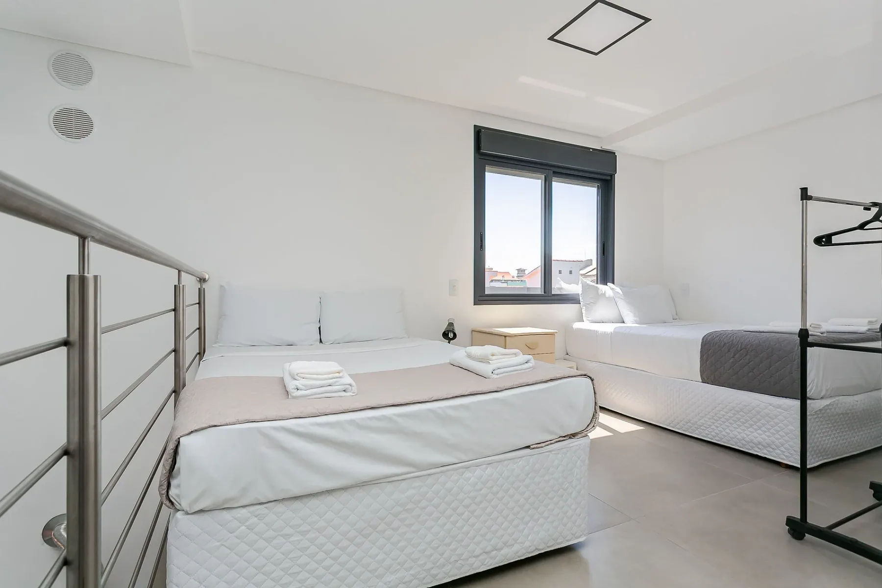 A bright bedroom with two beds and a window.