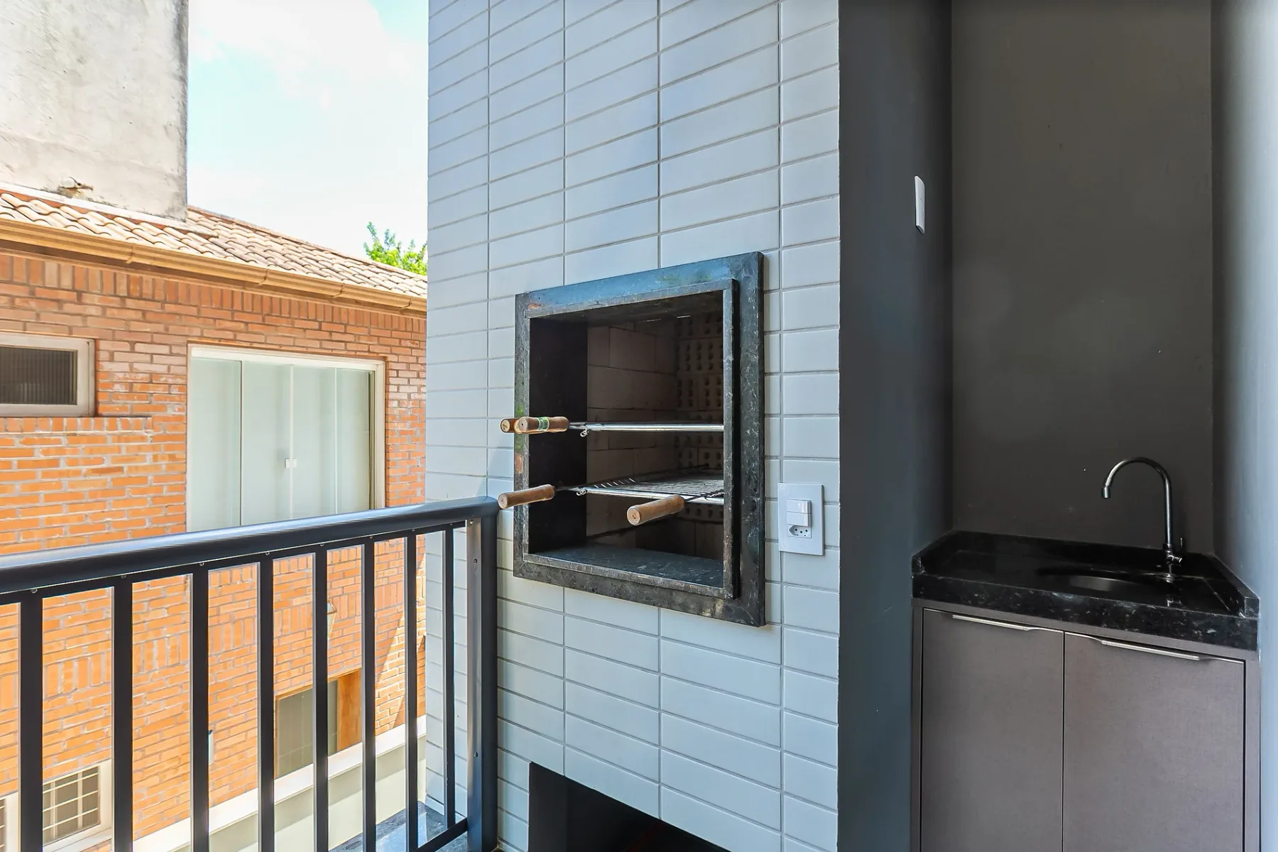 A balcony grilling area with a built-in grill and a small sink.