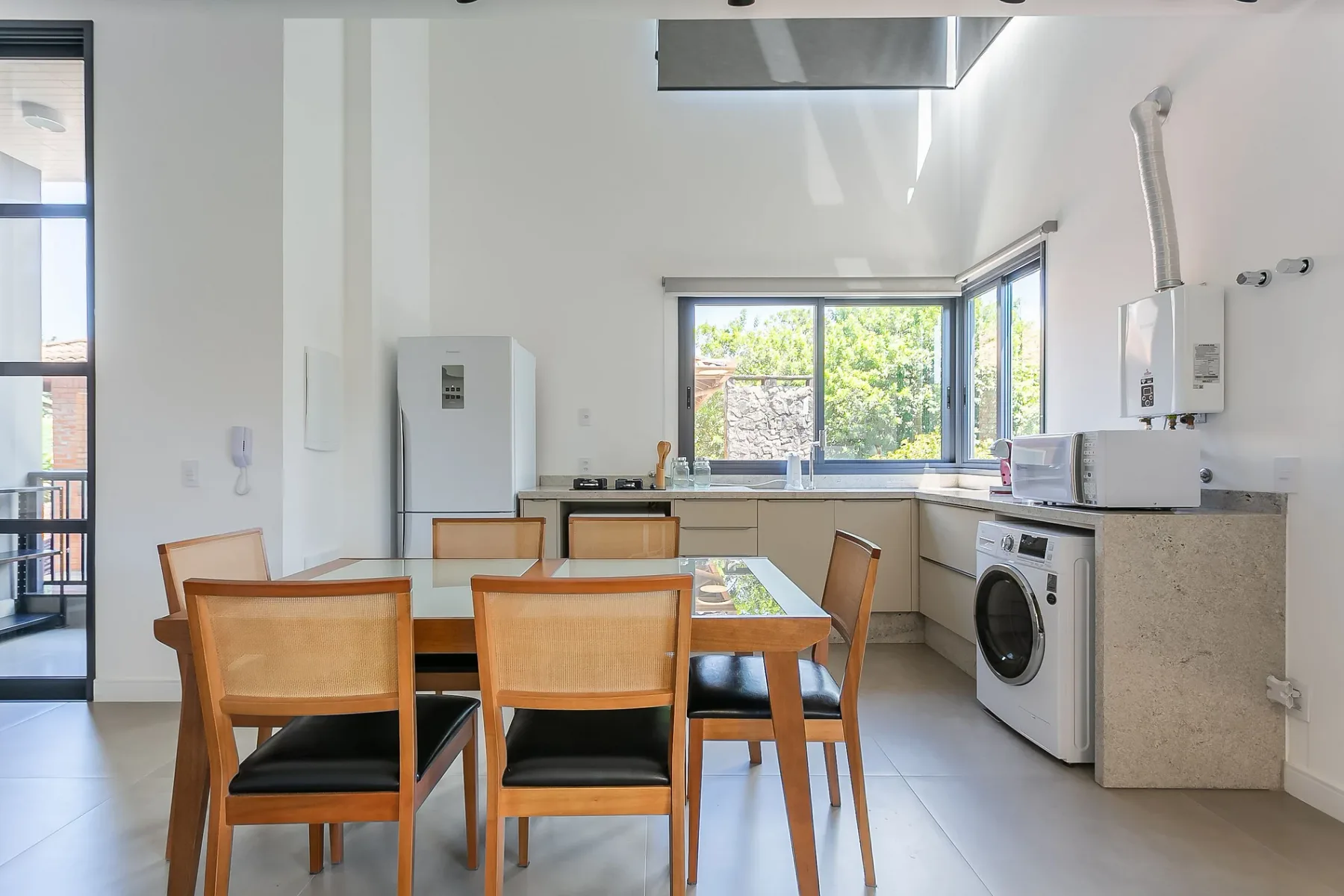 A bright kitchen and dining area with wooden seating and large windows.
