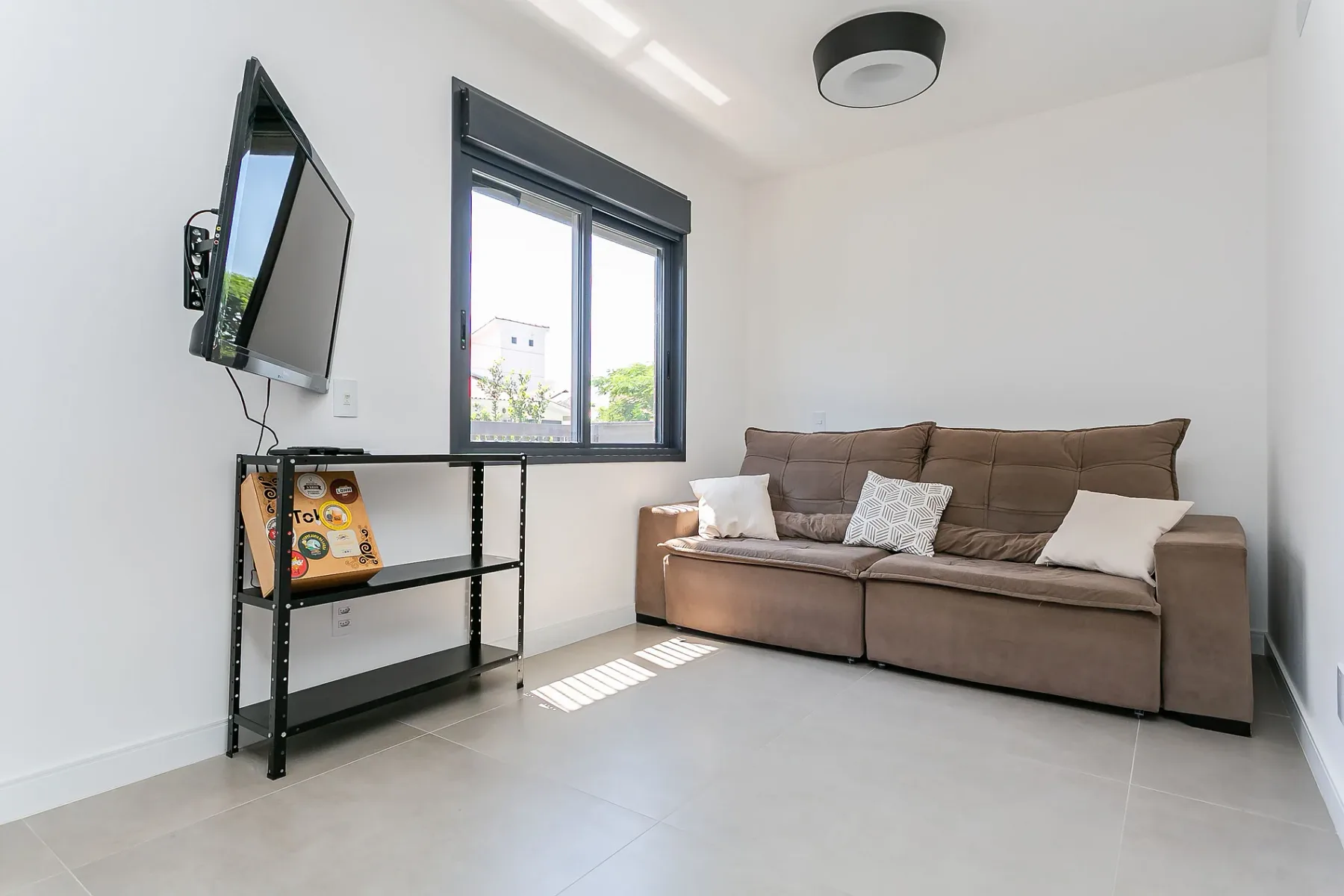 A bright living room with a brown sofa beneath a window.