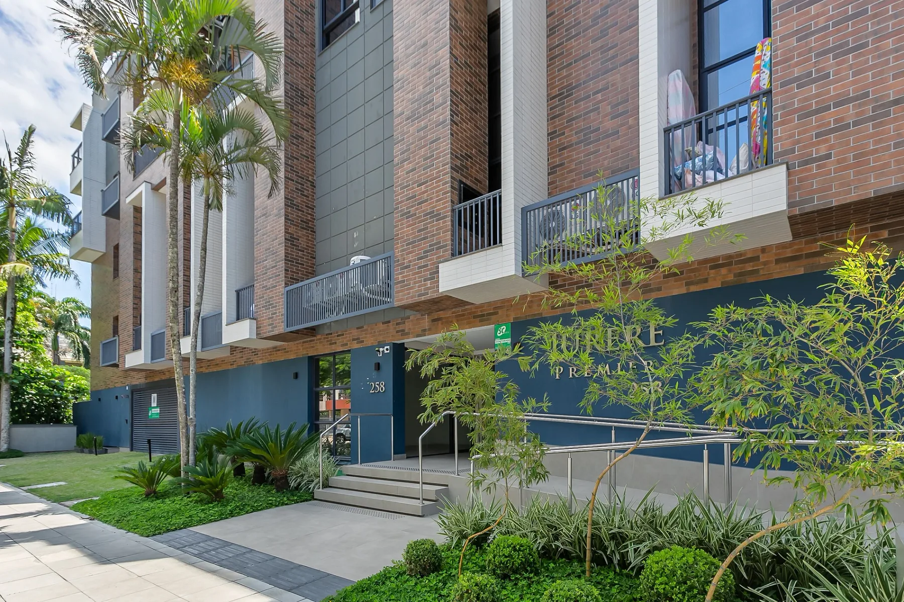 Shared amenity: A brick apartment building with balconies, landscaped plants, and a paved walkway.