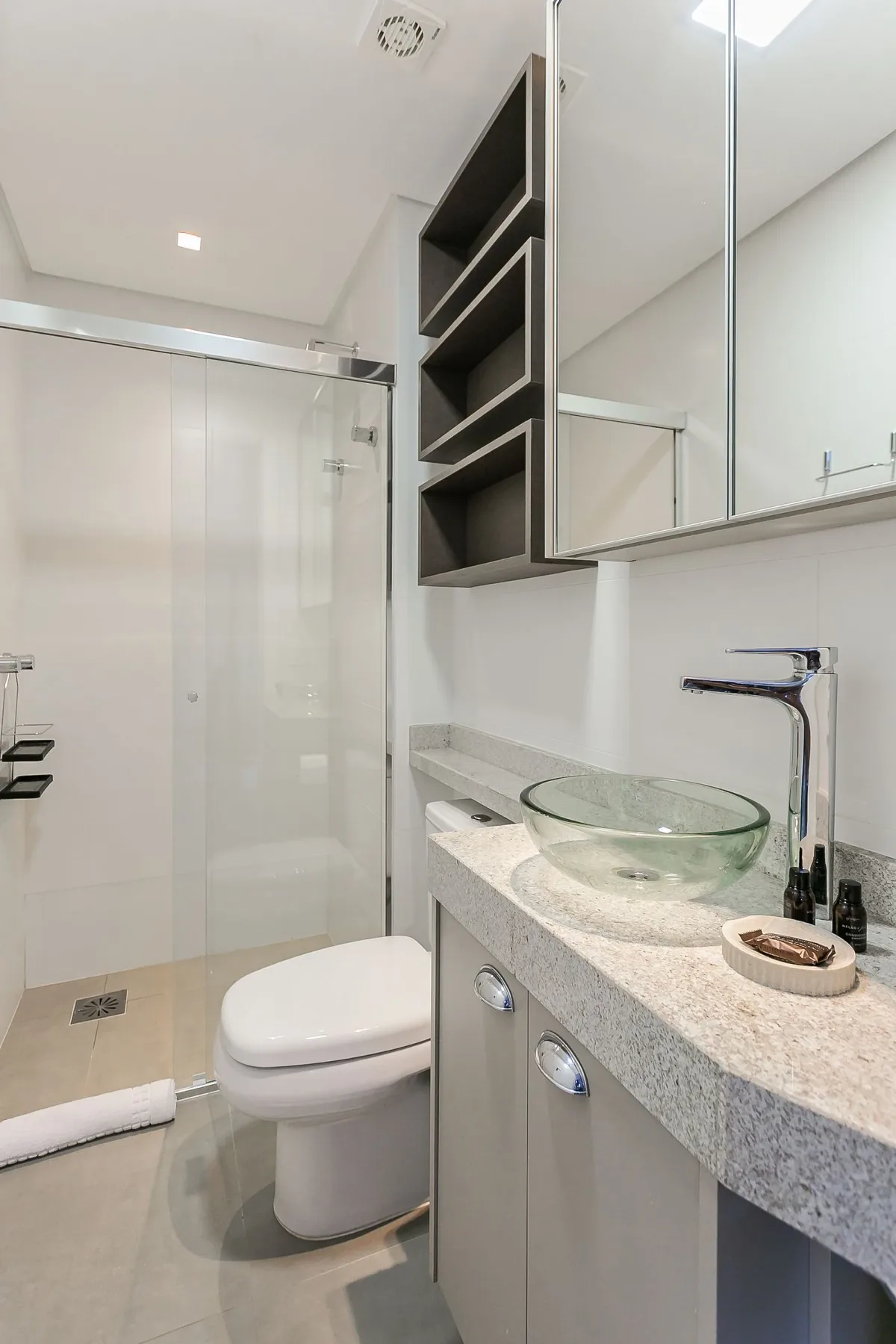 A modern bathroom with a glass shower, toilet, and sink.