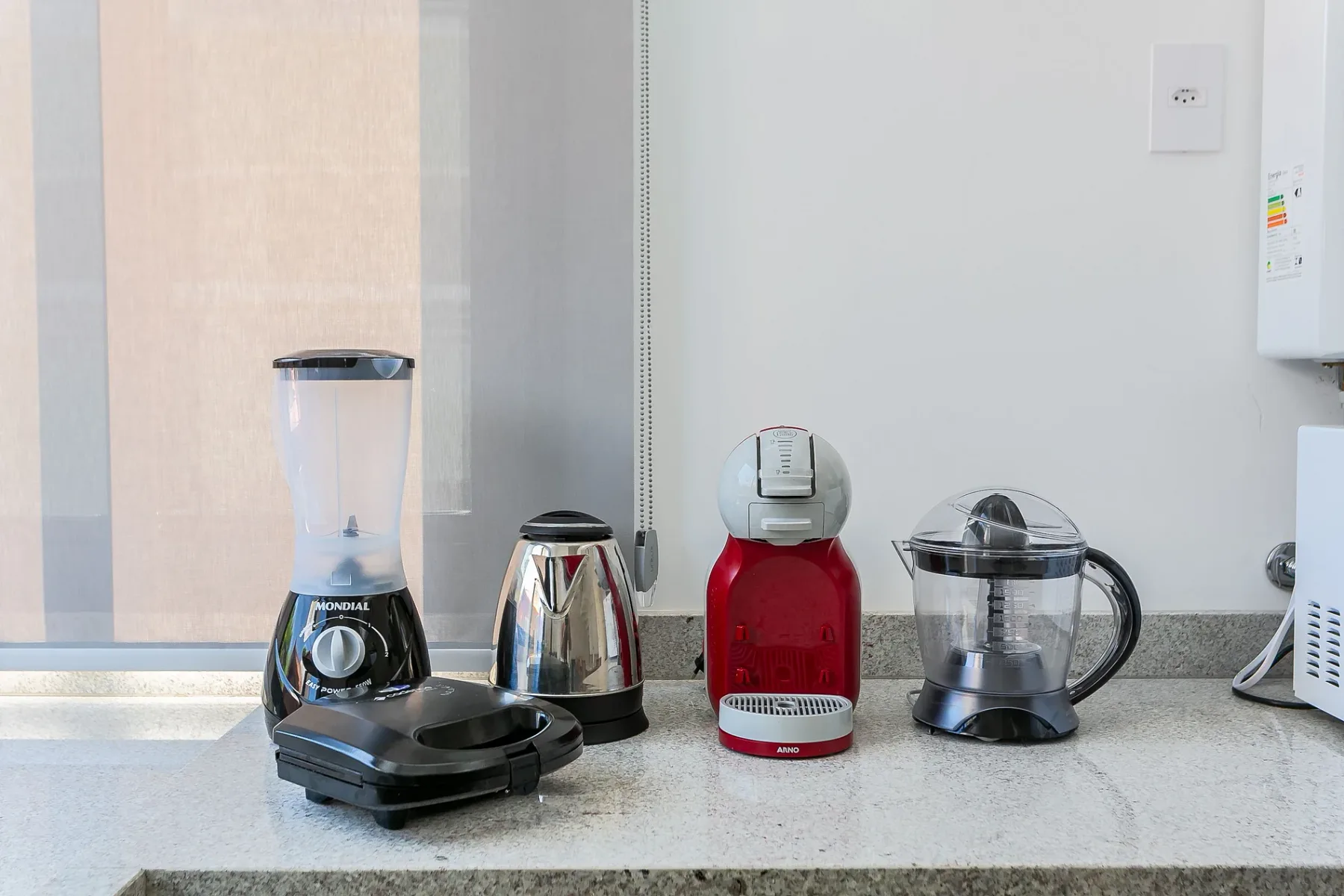 Kitchen counter with a blender, kettle, coffee machine, and glass pot.