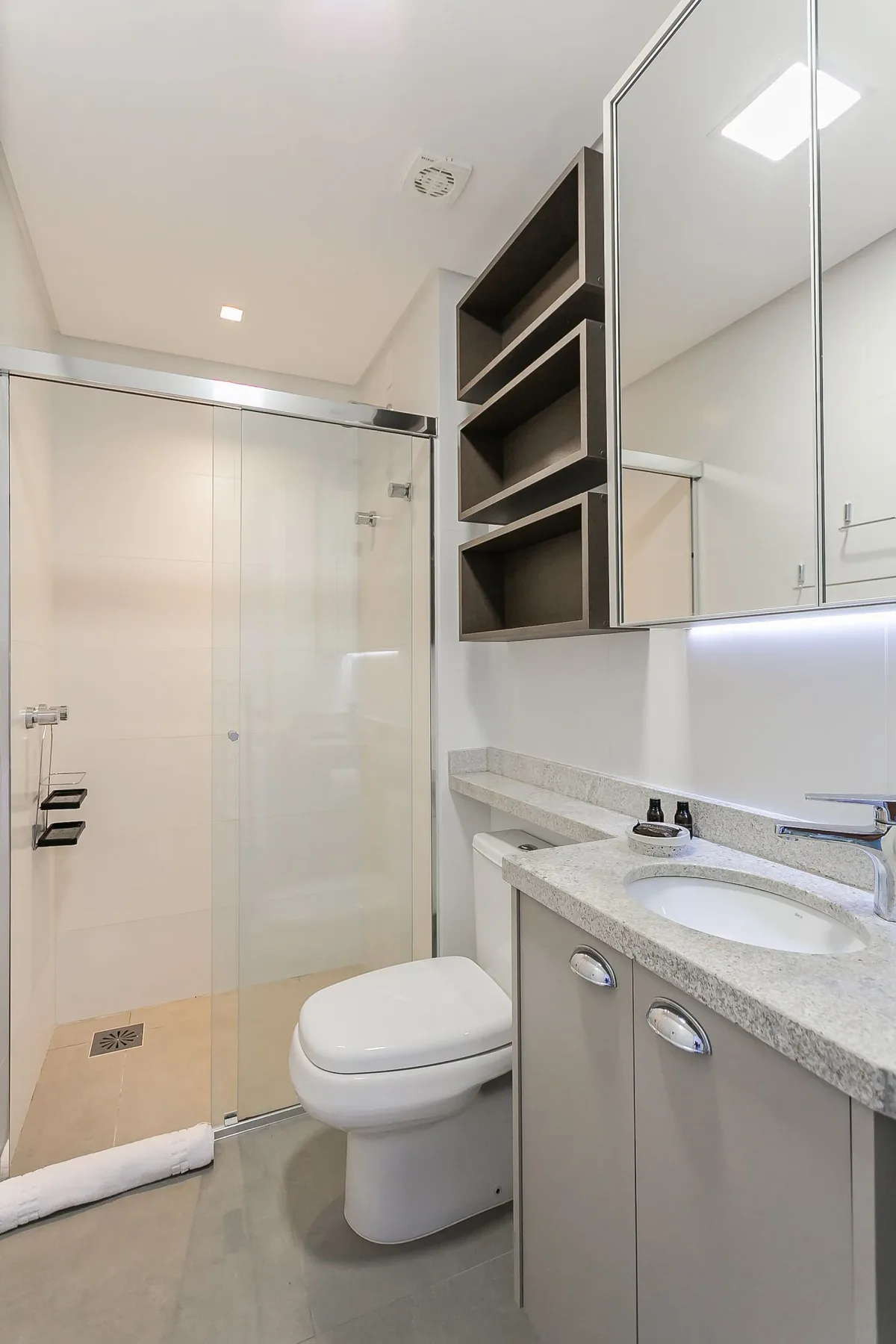 A bathroom with a glass shower, toilet, and vanity.