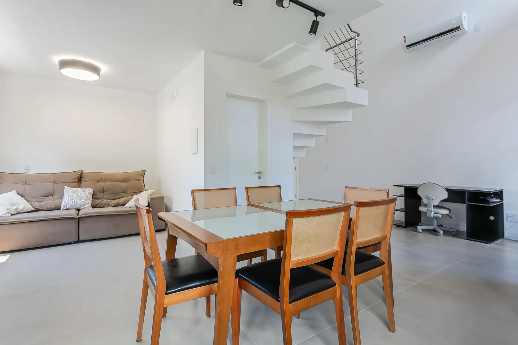 A dining area with a wooden table and seating beside a living area.
