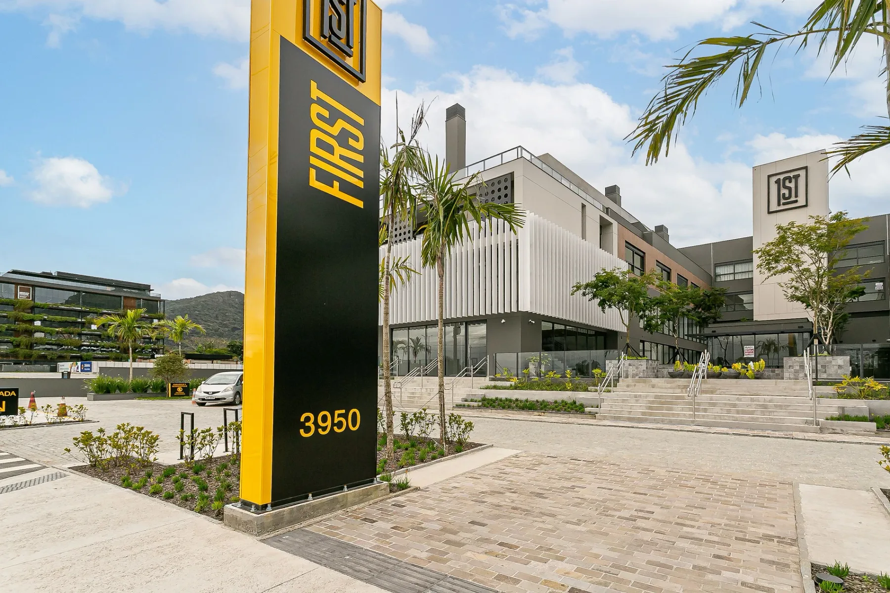 Shared amenity: Modern commercial building entrance with a tall sign beside the paved forecourt.