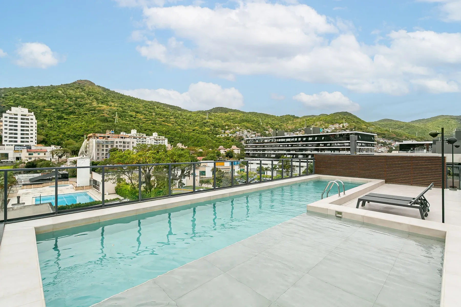 Shared amenity: A rooftop swimming pool overlooks surrounding buildings and green hills.