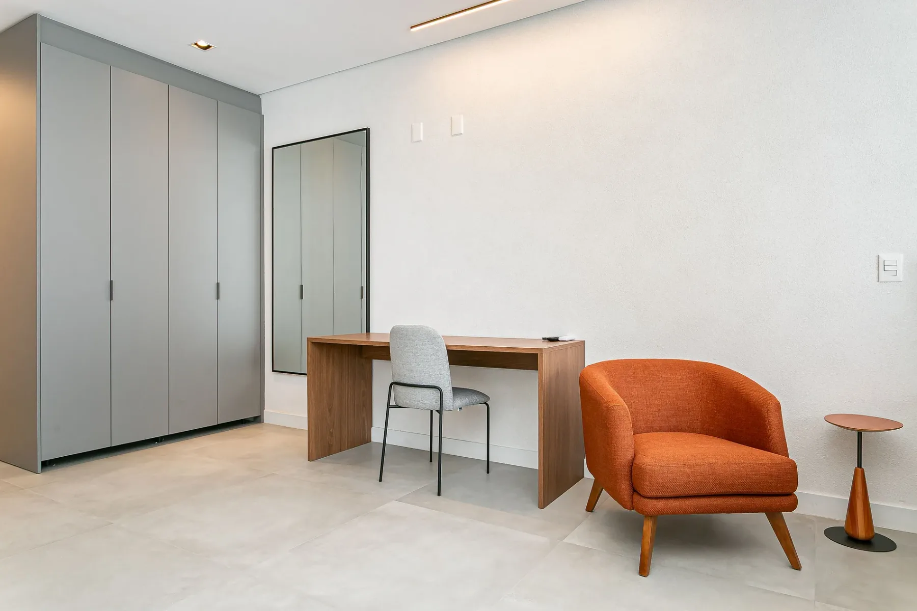A bright, modern room with a desk, seating, and built-in cabinets.