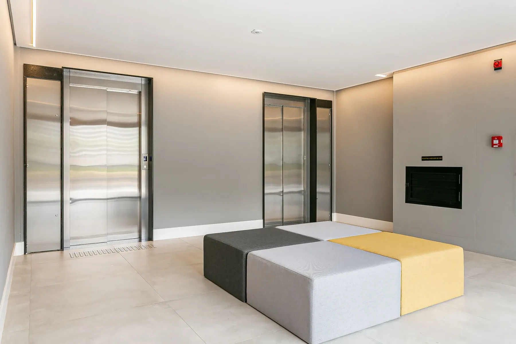 Shared amenity: An indoor elevator lobby with two elevators and padded seating.