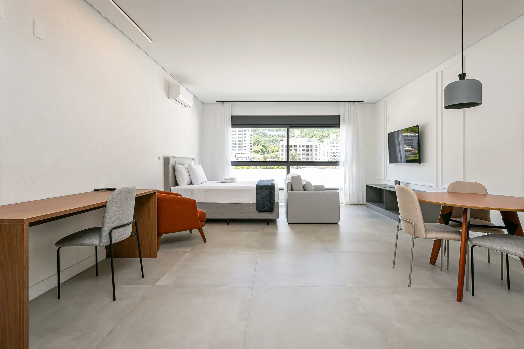 A bright bedroom with a bed, seating, and a dining table.