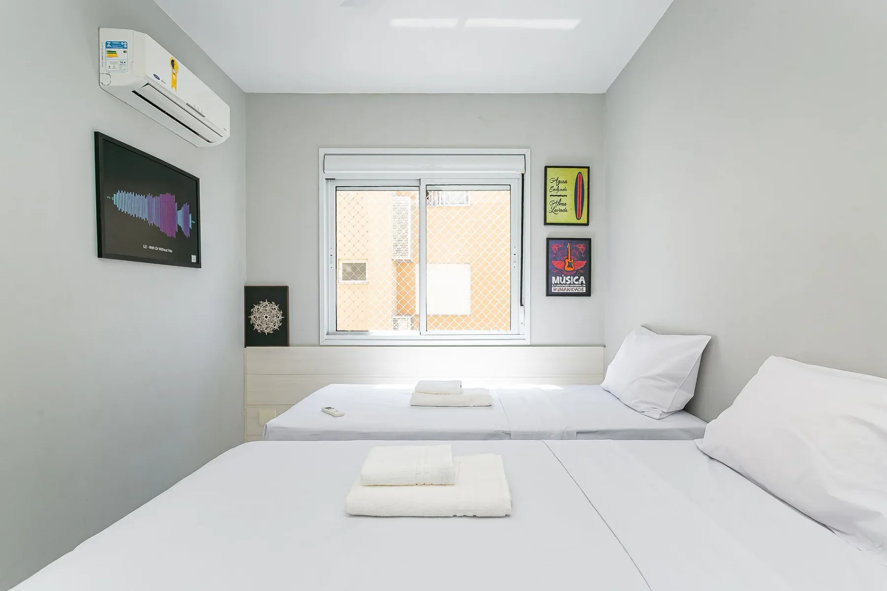A bright bedroom with two beds and a window.