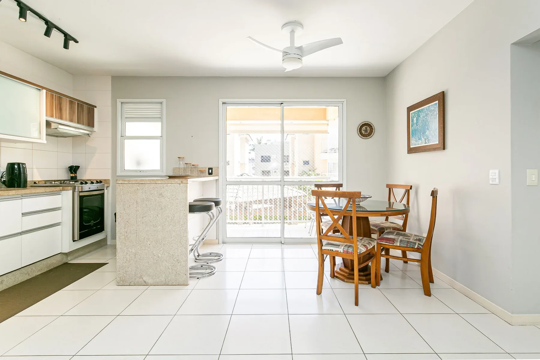 A bright kitchen and dining area with a table beside sliding glass doors.
