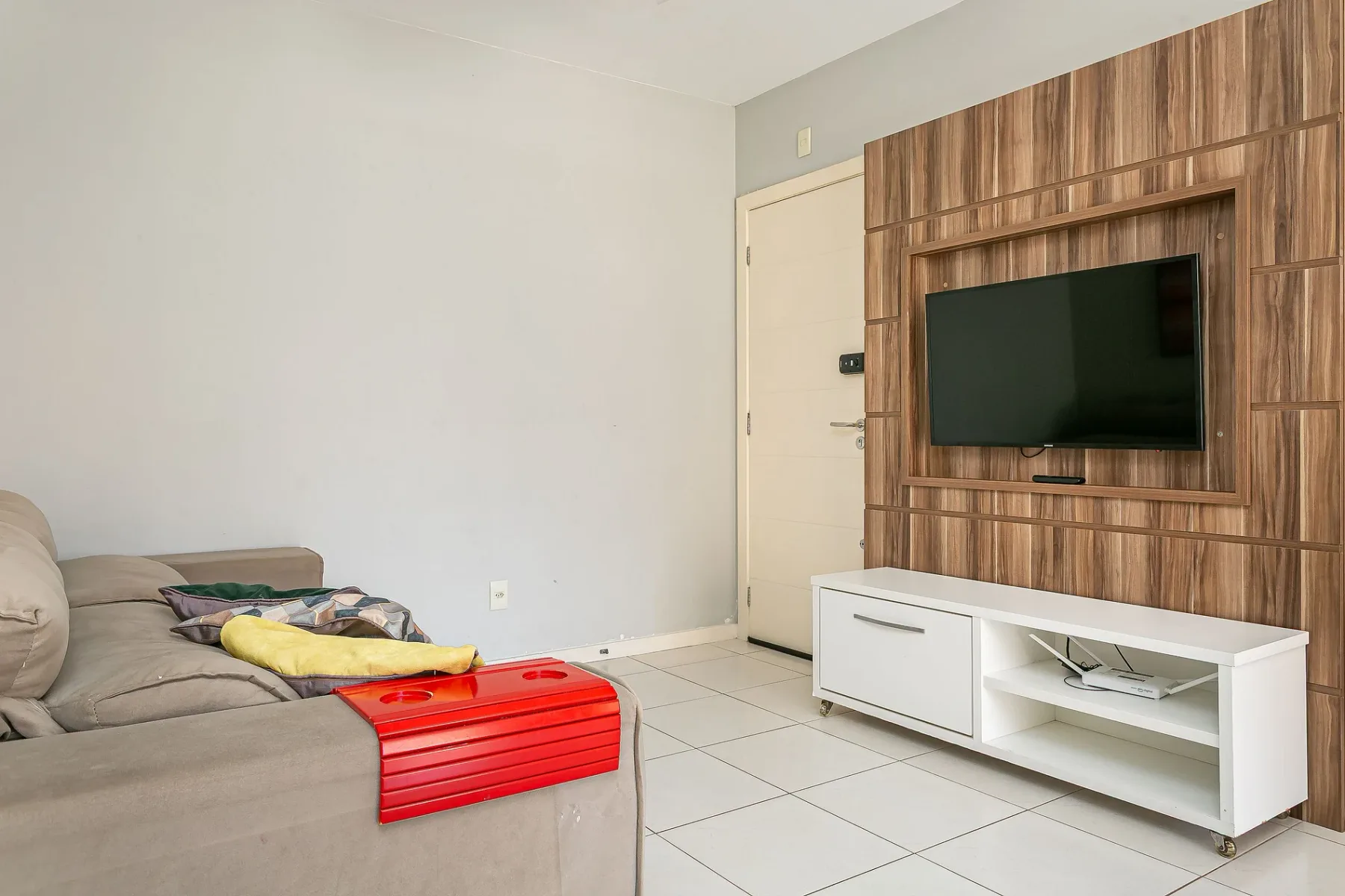 A living room with a television mounted above a white media console.