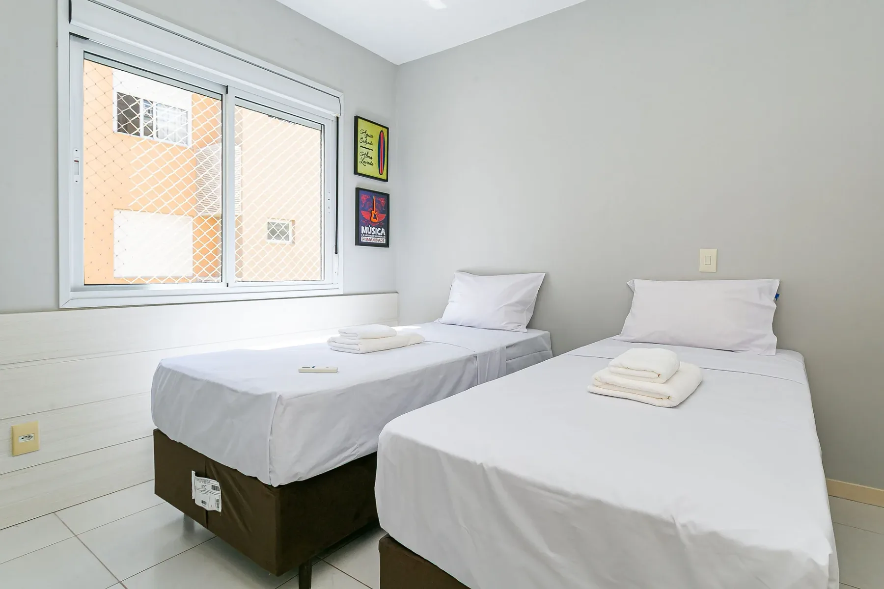 A bedroom with two single beds beside a large window.