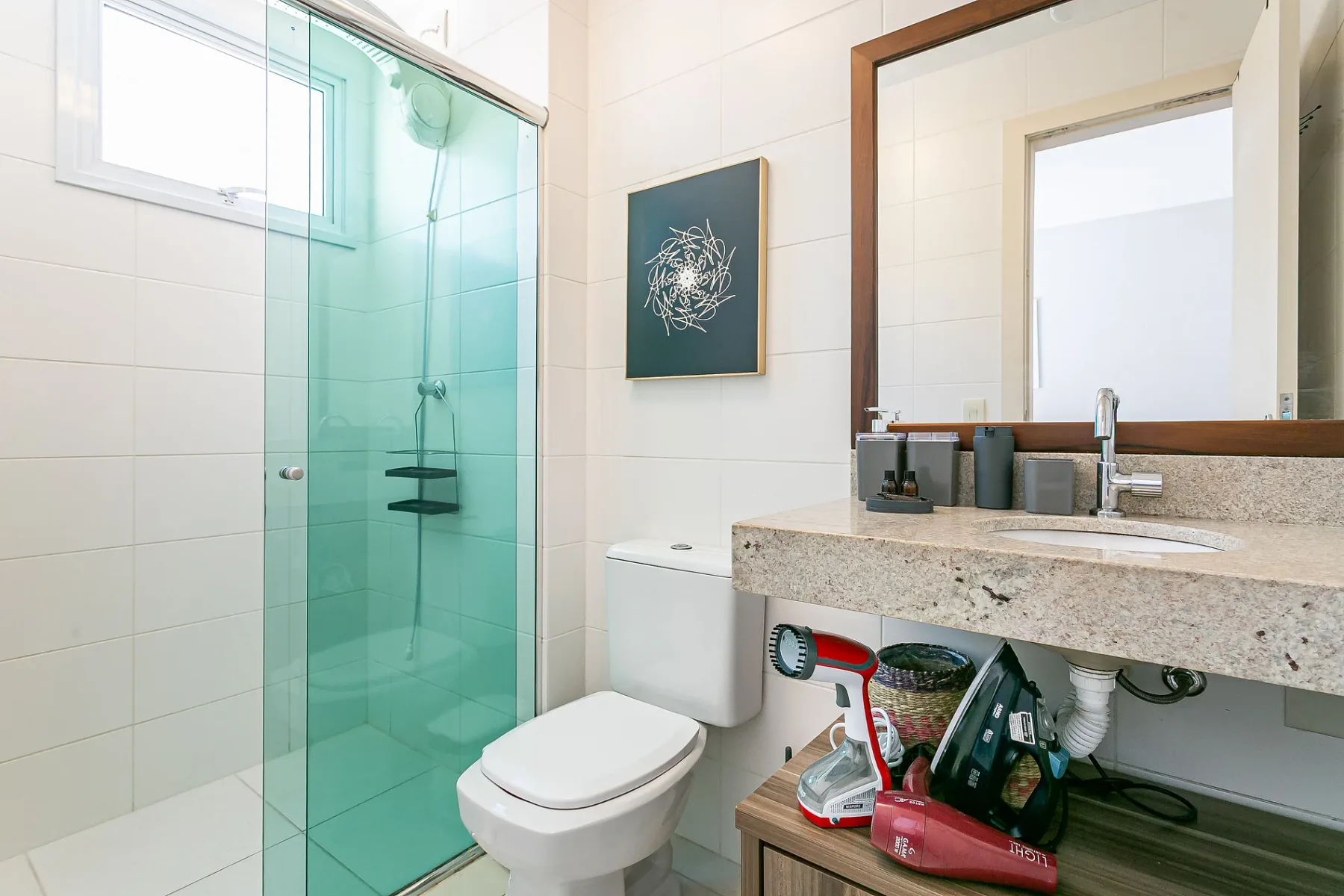 A bright tiled bathroom with a glass shower and sink vanity.