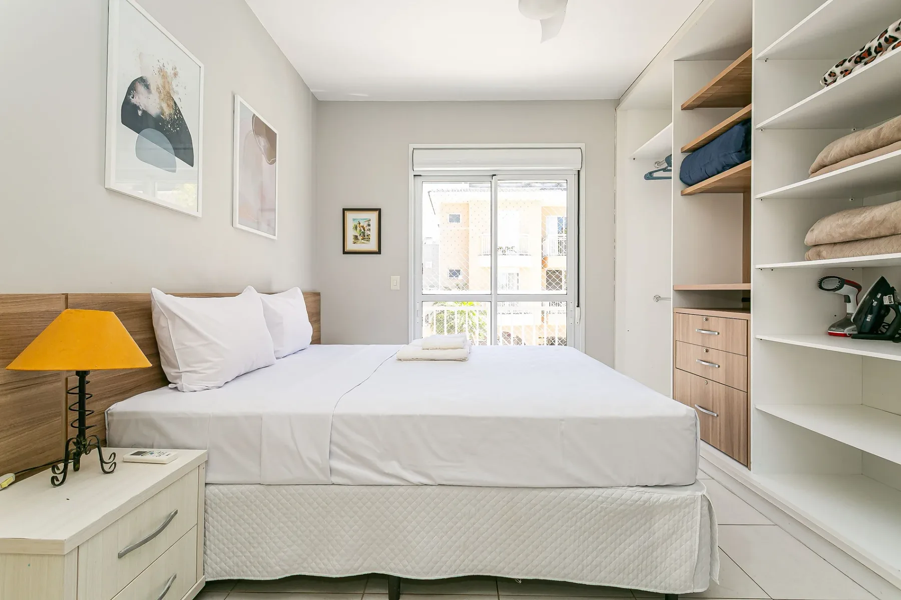 A bright bedroom with a neatly made bed and built-in shelving.