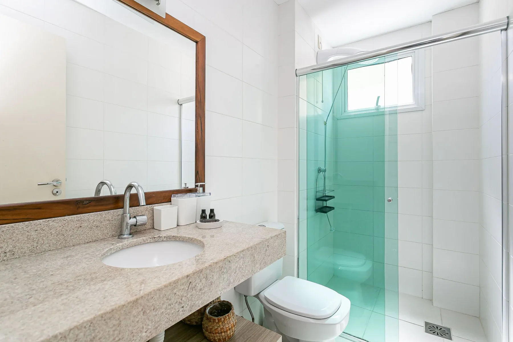 A bright bathroom with a sink, mirror, and glass shower.
