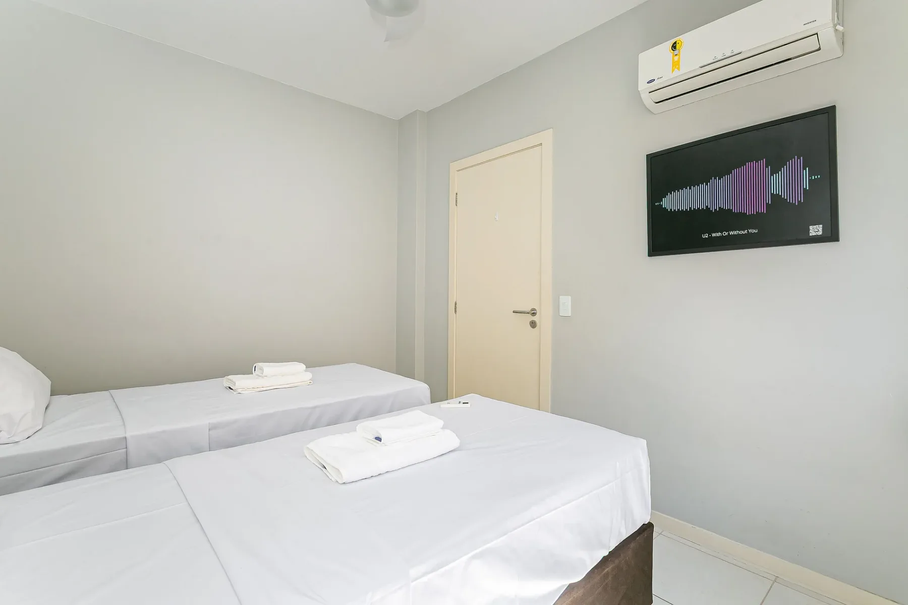 A bedroom with two beds and a wall-mounted air conditioner.