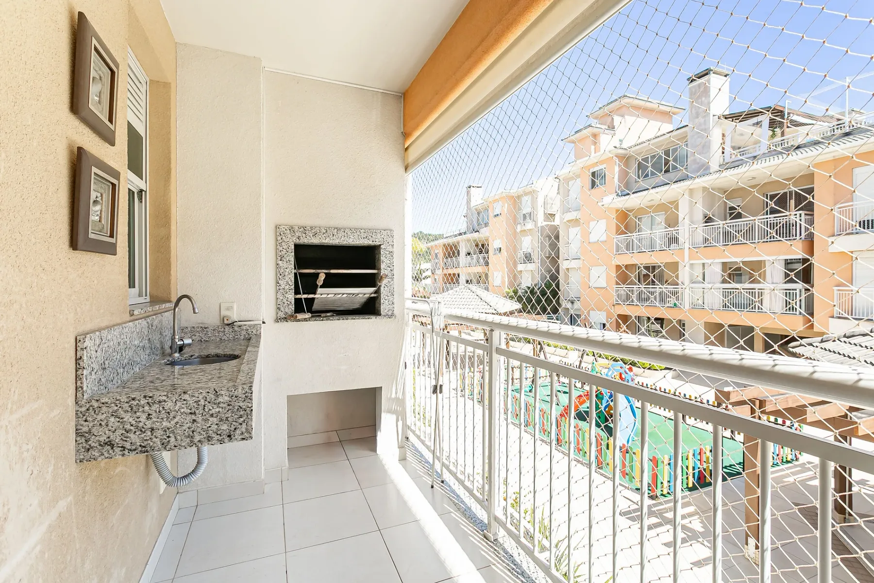 A balcony with a built-in grill and a view of nearby buildings.