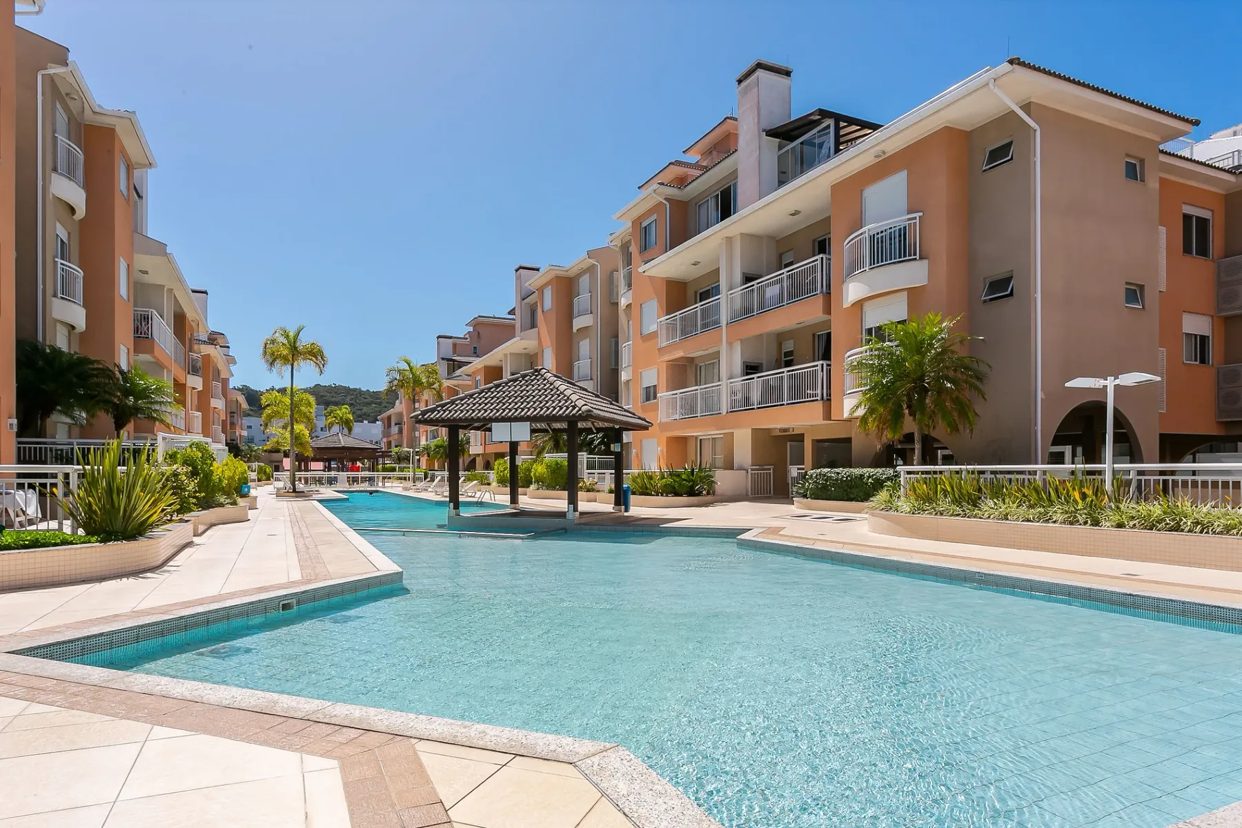 Shared amenity: A swimming pool sits between apartment buildings, with a shaded pavilion beside it.