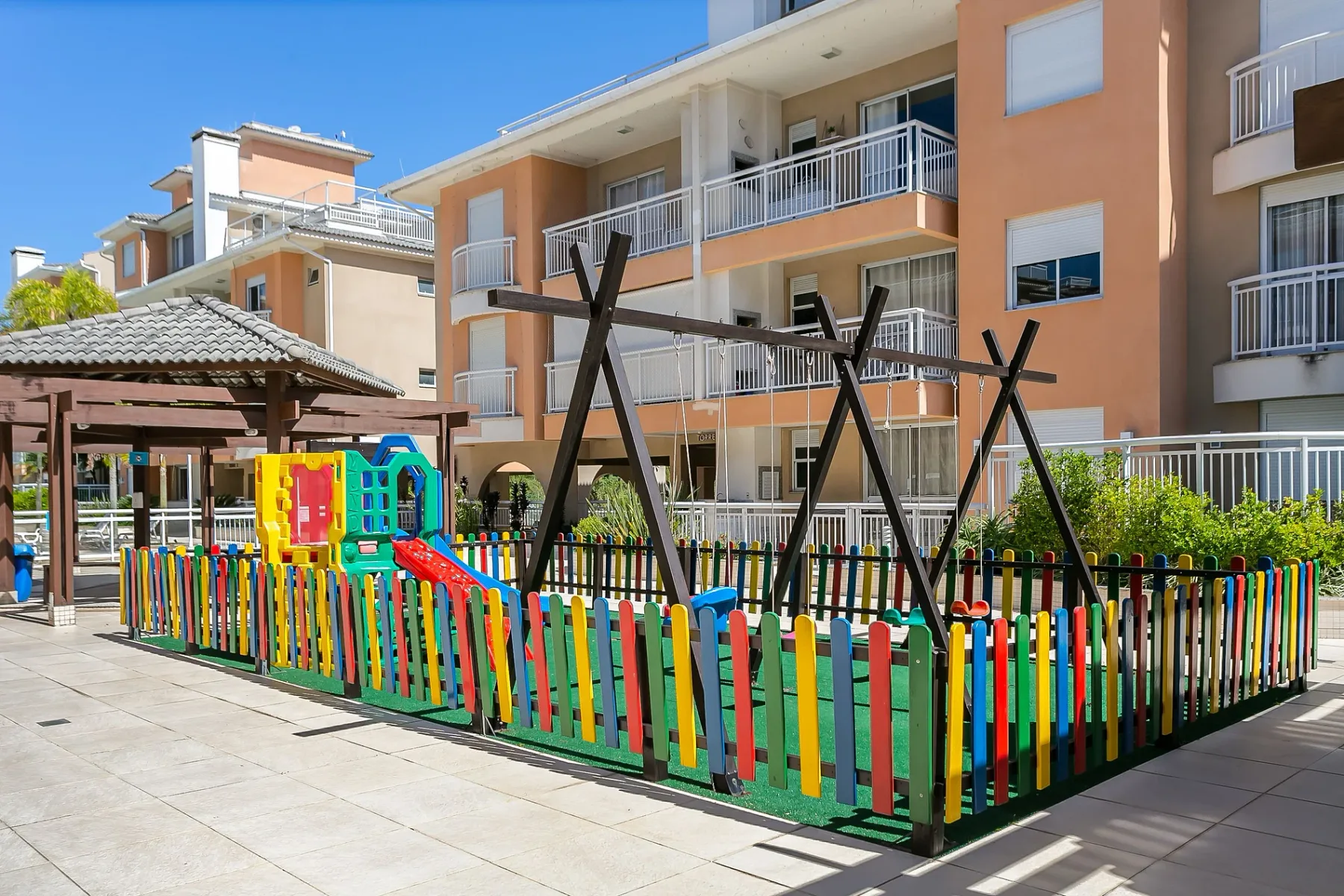 Shared amenity: An outdoor playground with colorful fencing beside an apartment building.