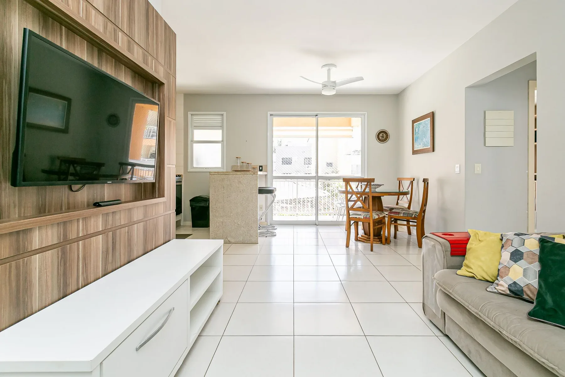 A bright living and dining area has tiled floors and sliding glass doors.