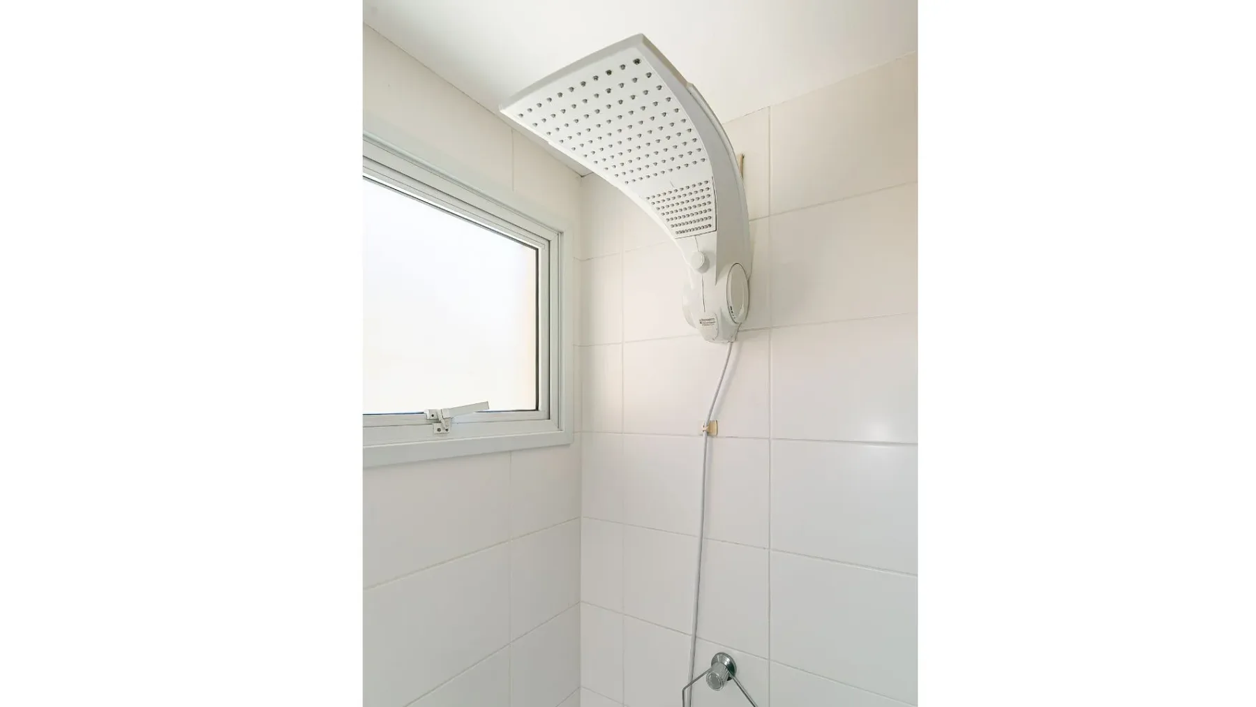 A tiled bathroom shower area with a large rainfall showerhead beside a window.