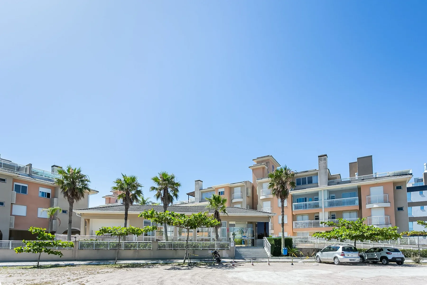 Shared amenity: Apartment buildings stand behind a landscaped outdoor area under a clear sky.