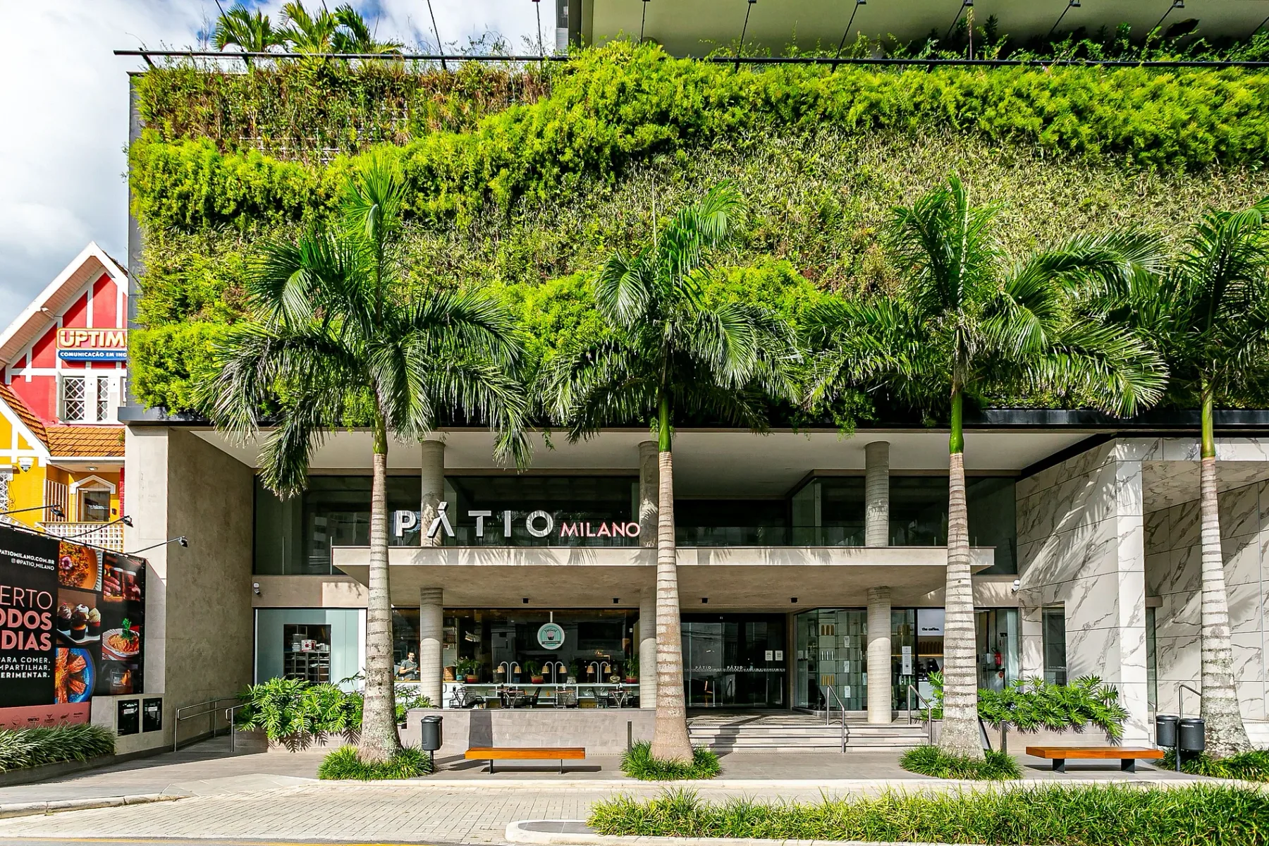 Shared amenity: A commercial building entrance with glass doors and palm trees in front.
