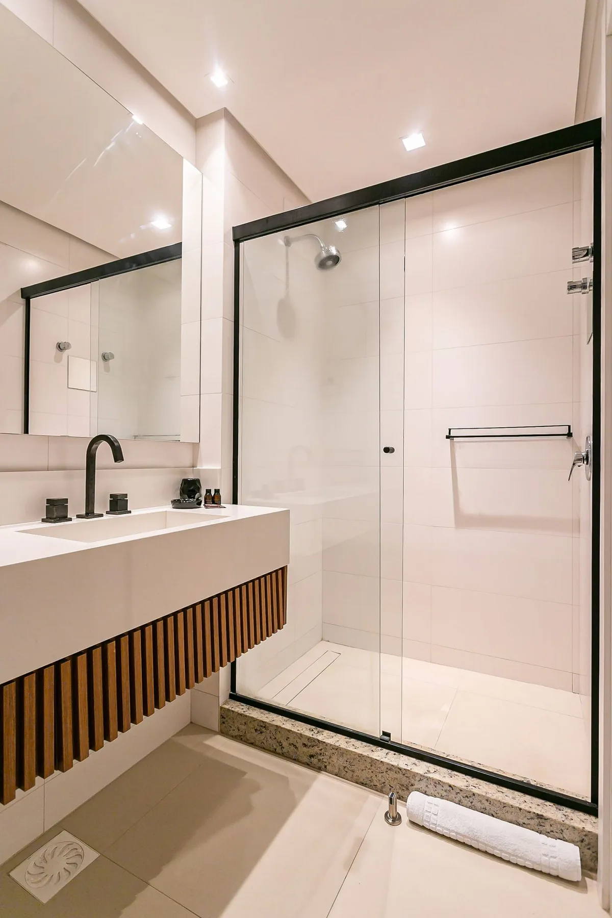 A bright bathroom with a glass shower and a long vanity.