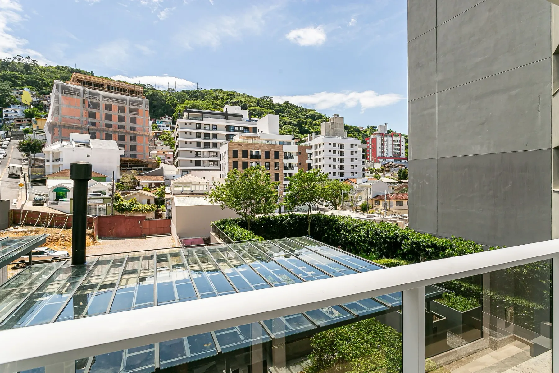 An elevated outdoor view overlooks city buildings and a green hillside.