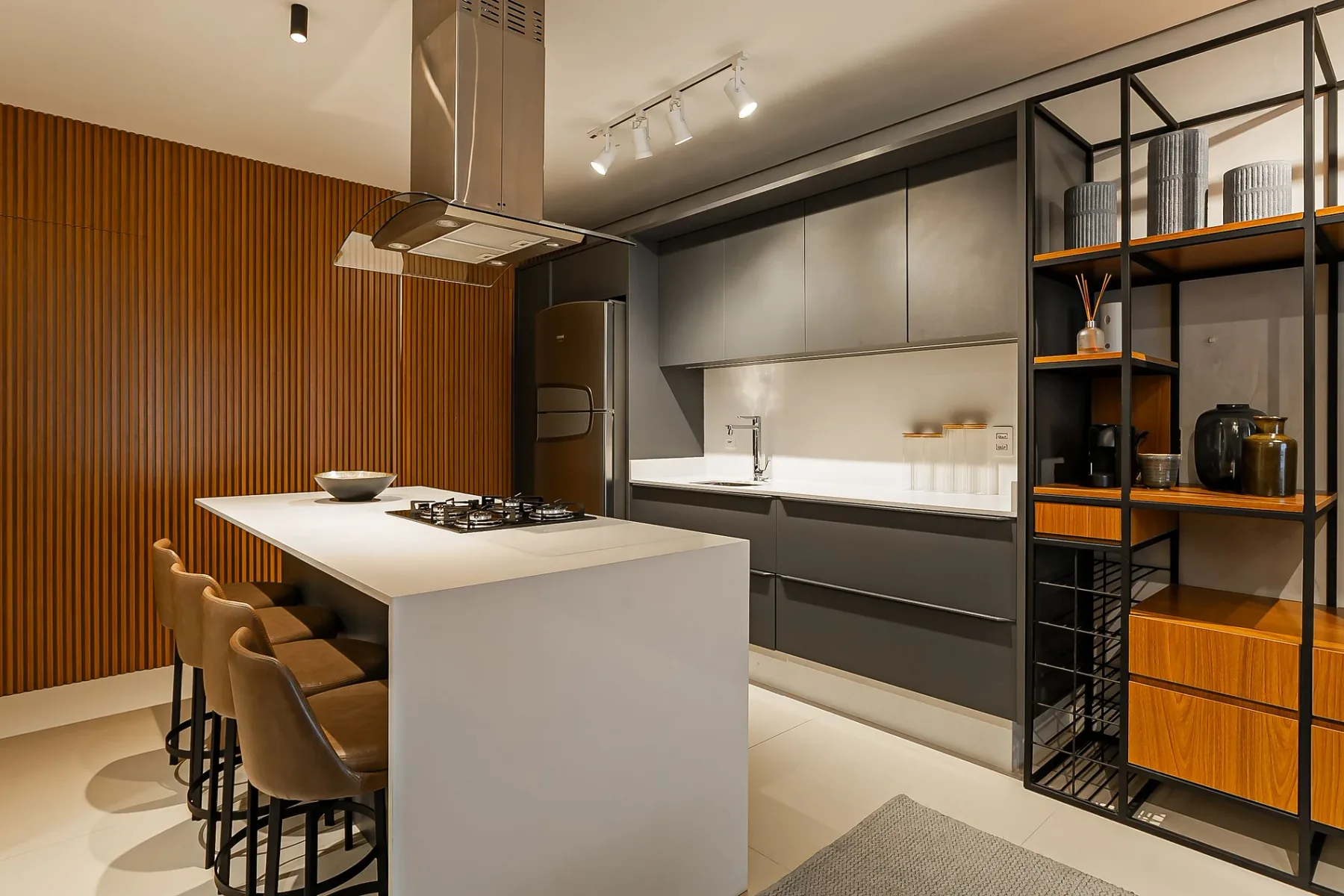 A modern kitchen with a large island, cooktop, and open shelving.