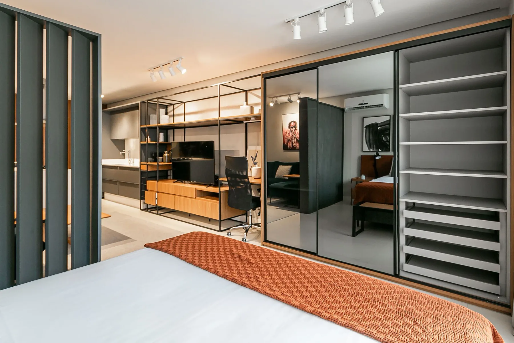 A modern bedroom with a bed, desk, and built-in shelving.