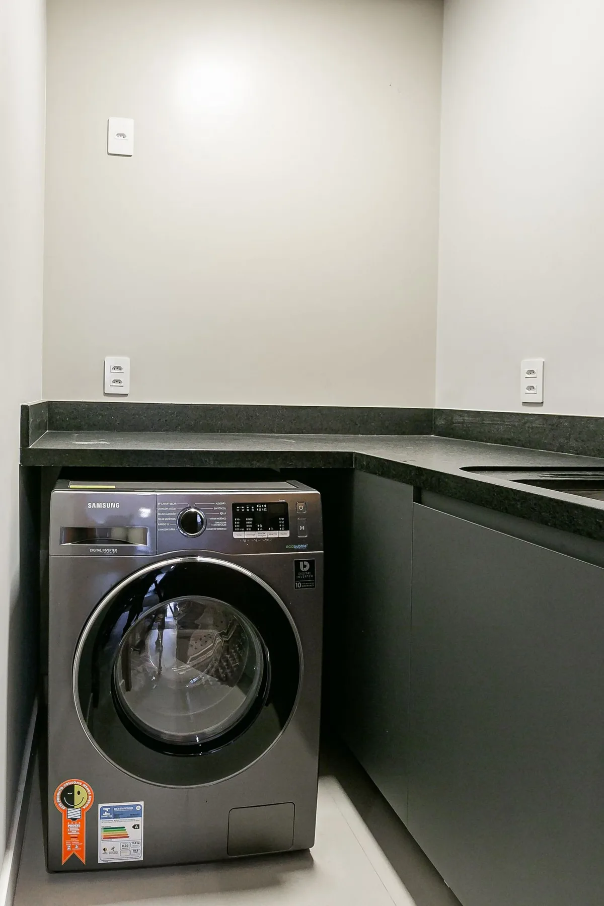 A laundry area with a front-loading washing machine beneath a dark countertop.