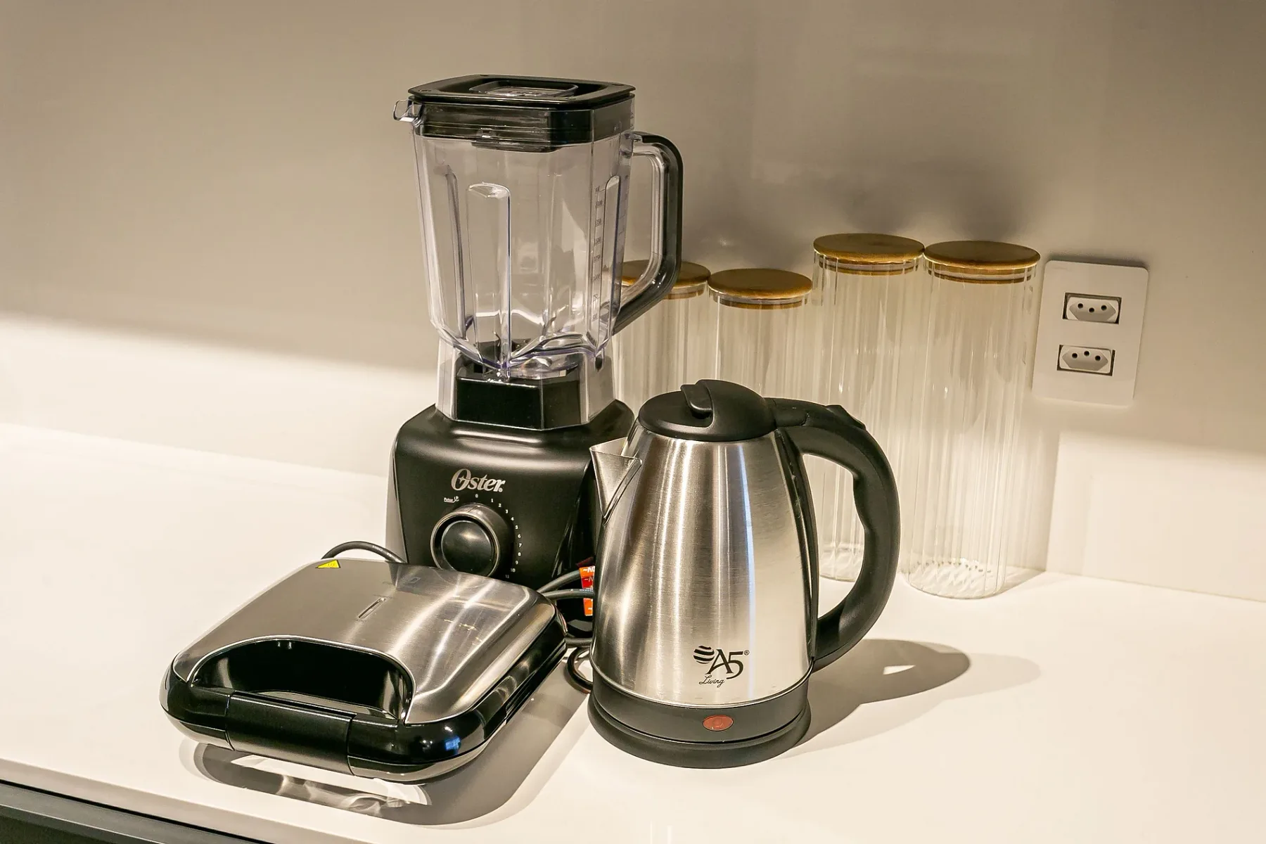 A kitchen counter with a blender, electric kettle, and sandwich press.