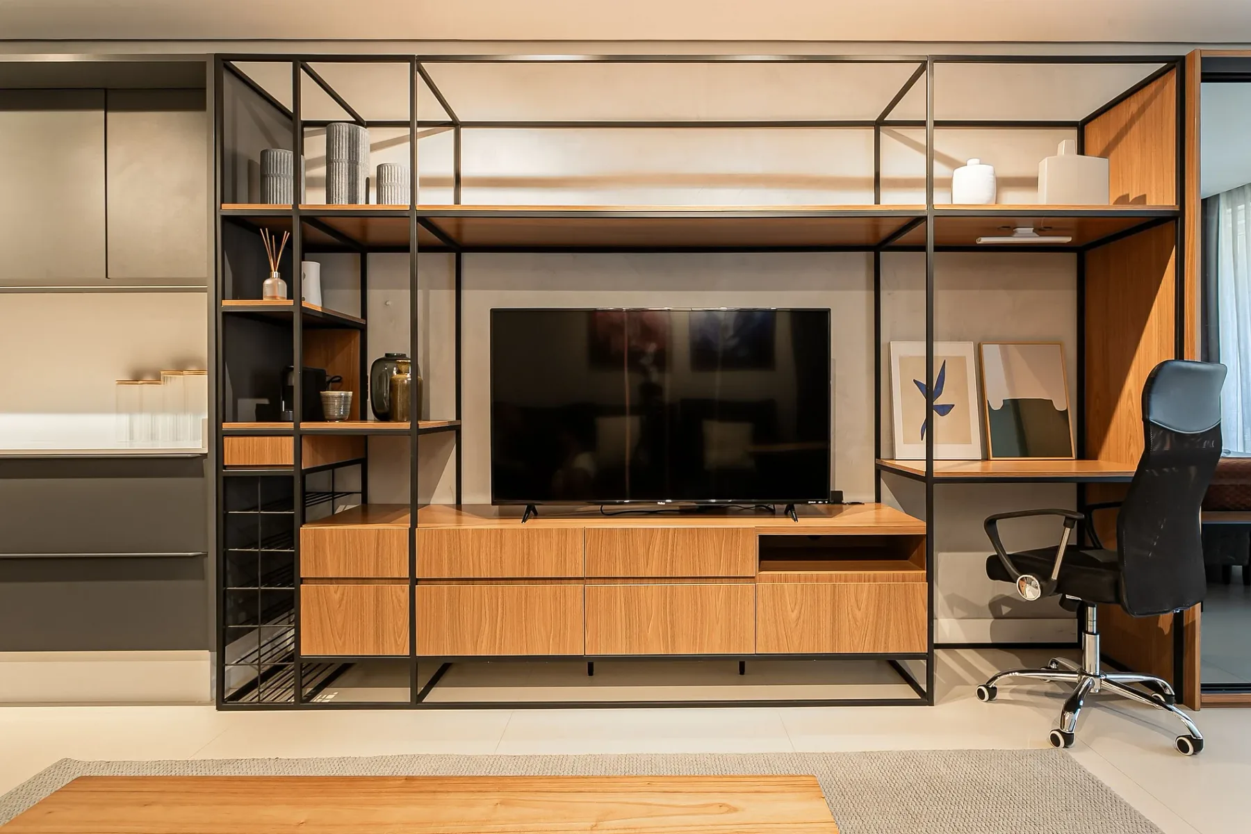 A living room media wall features a television, wood cabinetry, and open shelving.