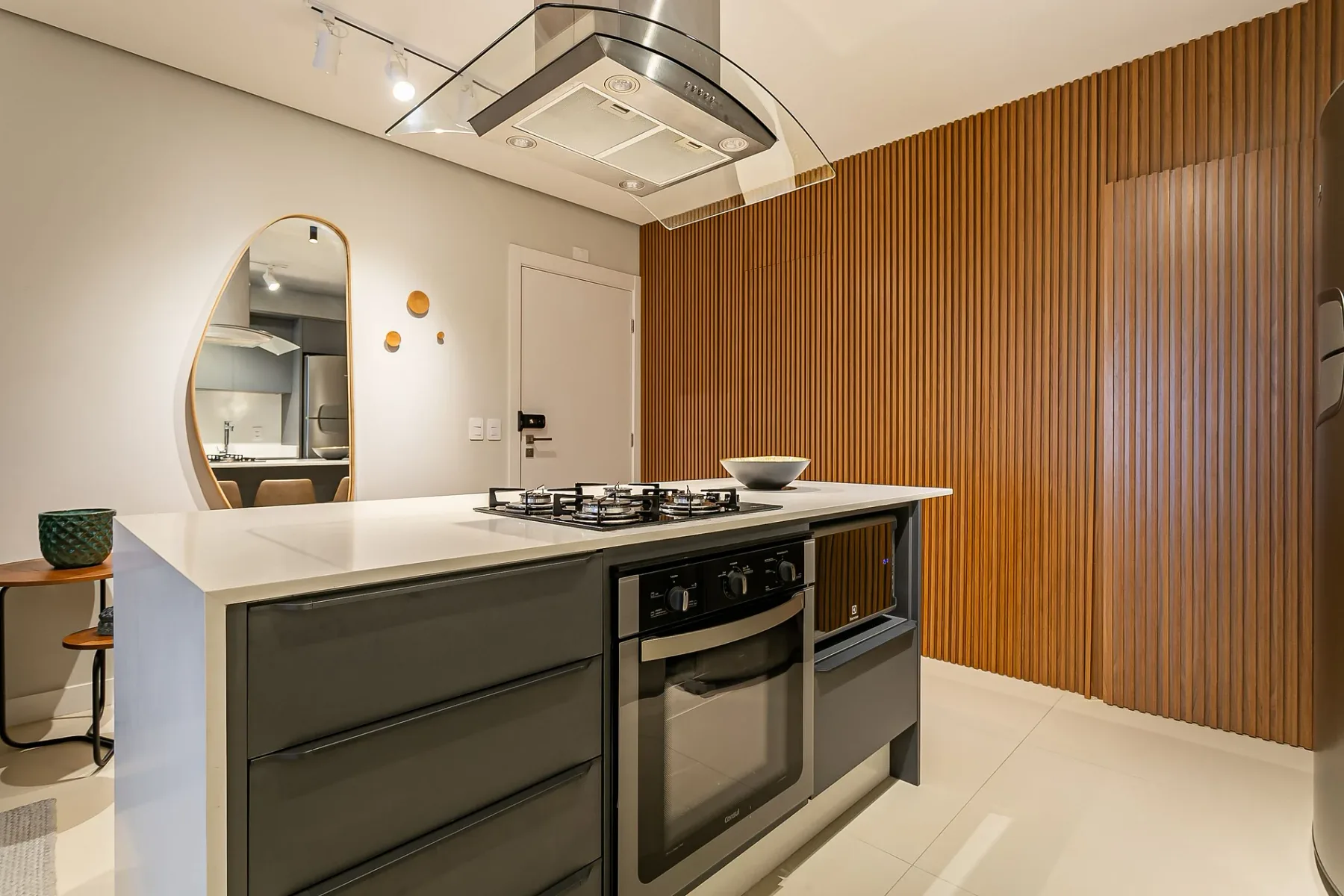 A modern kitchen with an island, cooktop, and wood slat wall.
