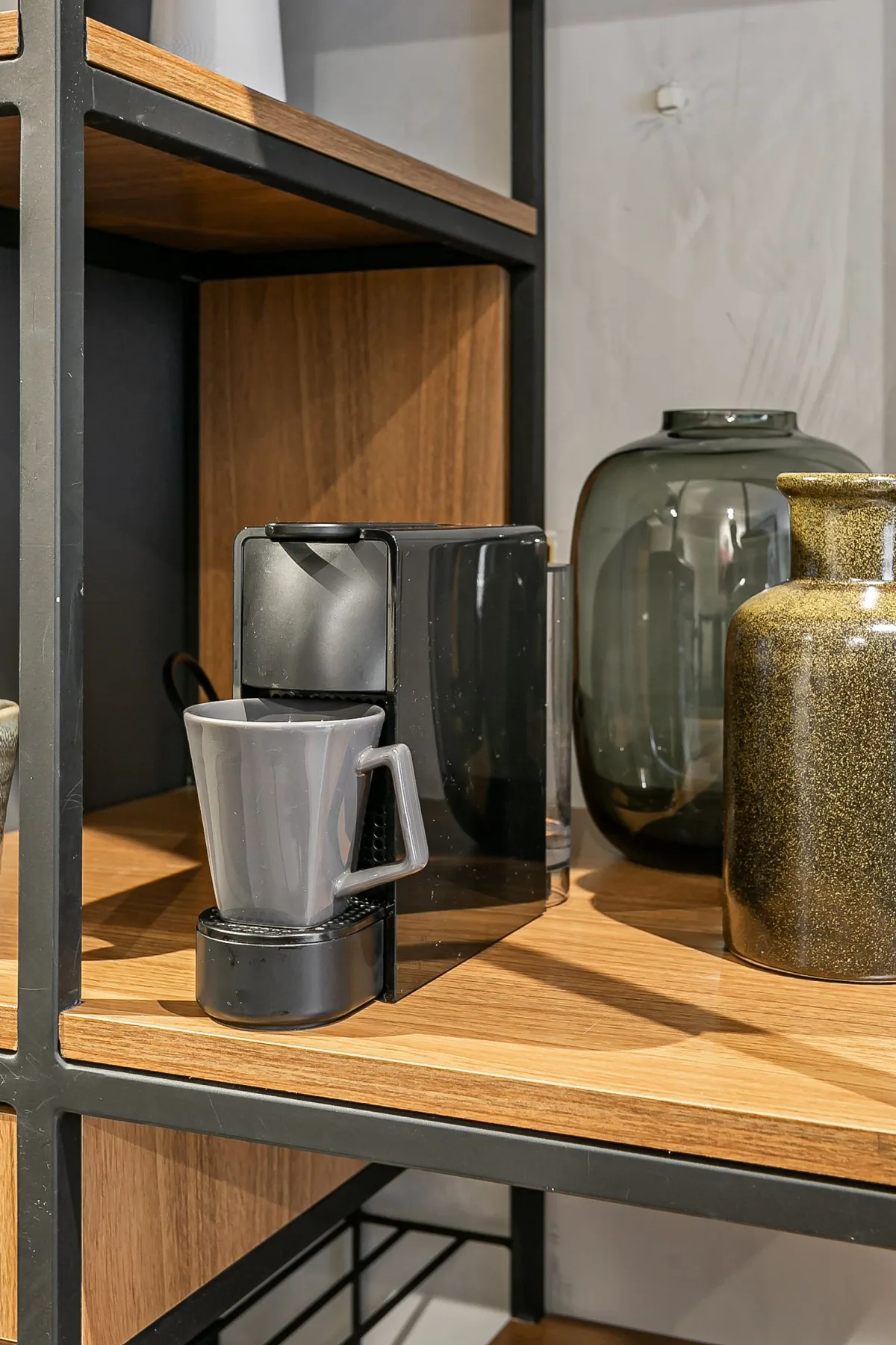 A coffee station with a pour-over brewer sits on a wooden shelf.