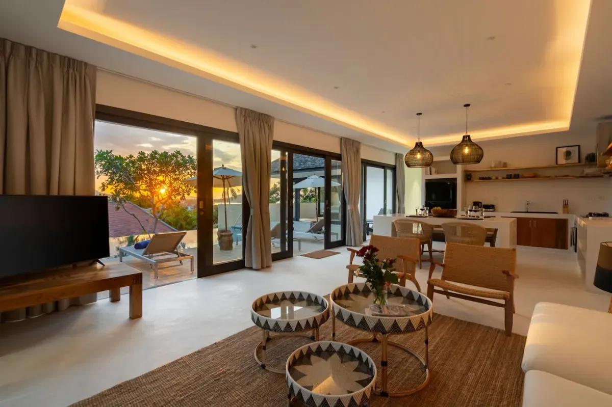 A bright living room opens onto a patio, with dining and kitchen areas beyond.