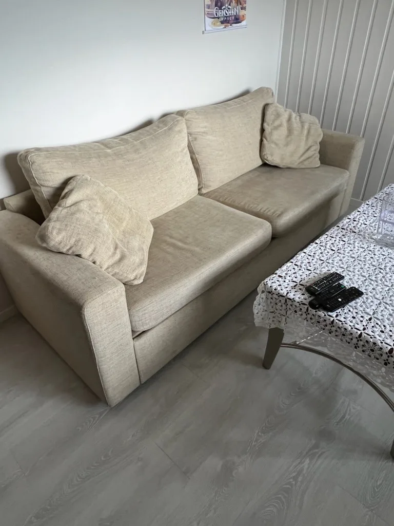 Una sala de estar con un sofá beige y una mesa baja.