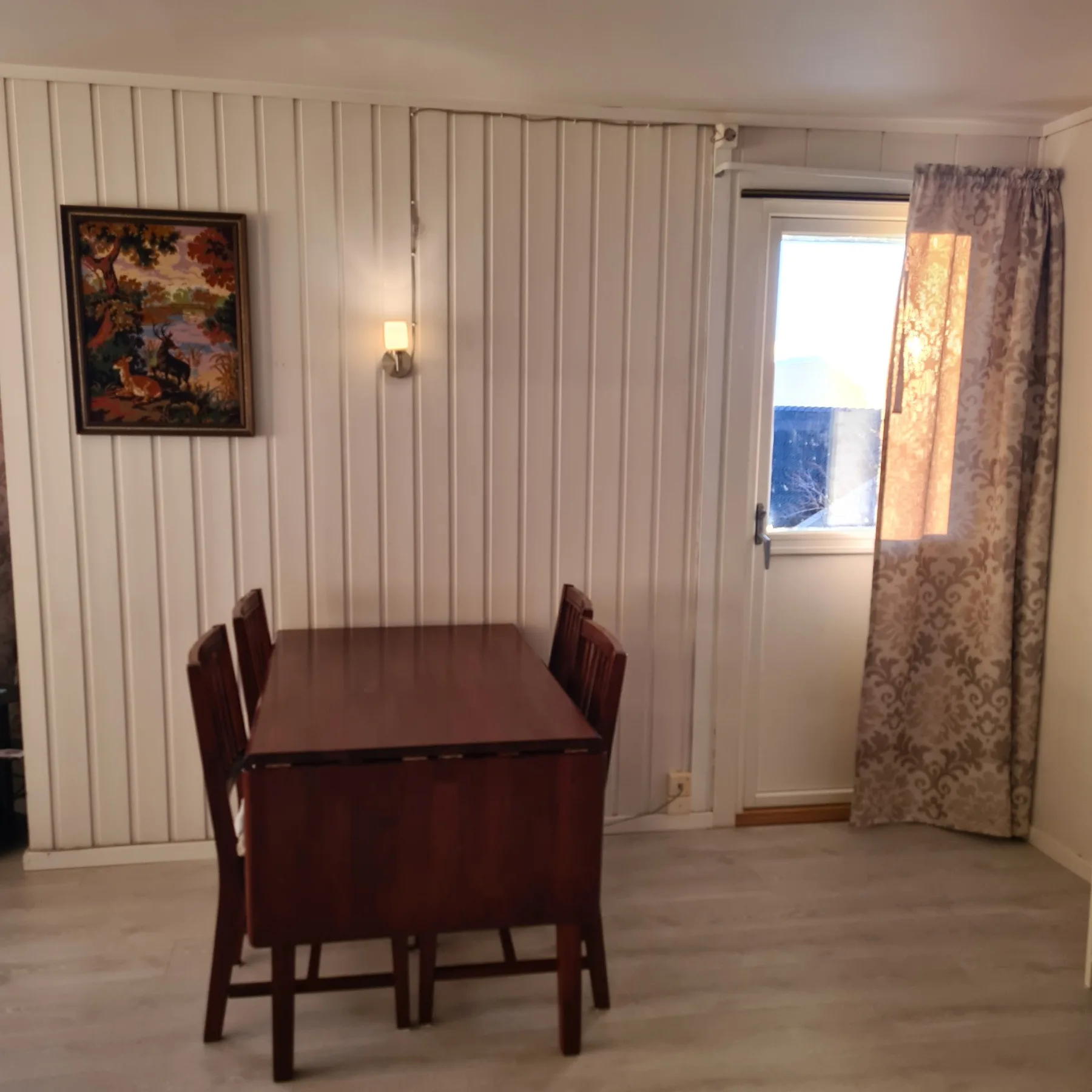Un comedor con una mesa de madera y sillas junto a una ventana con cortinas.