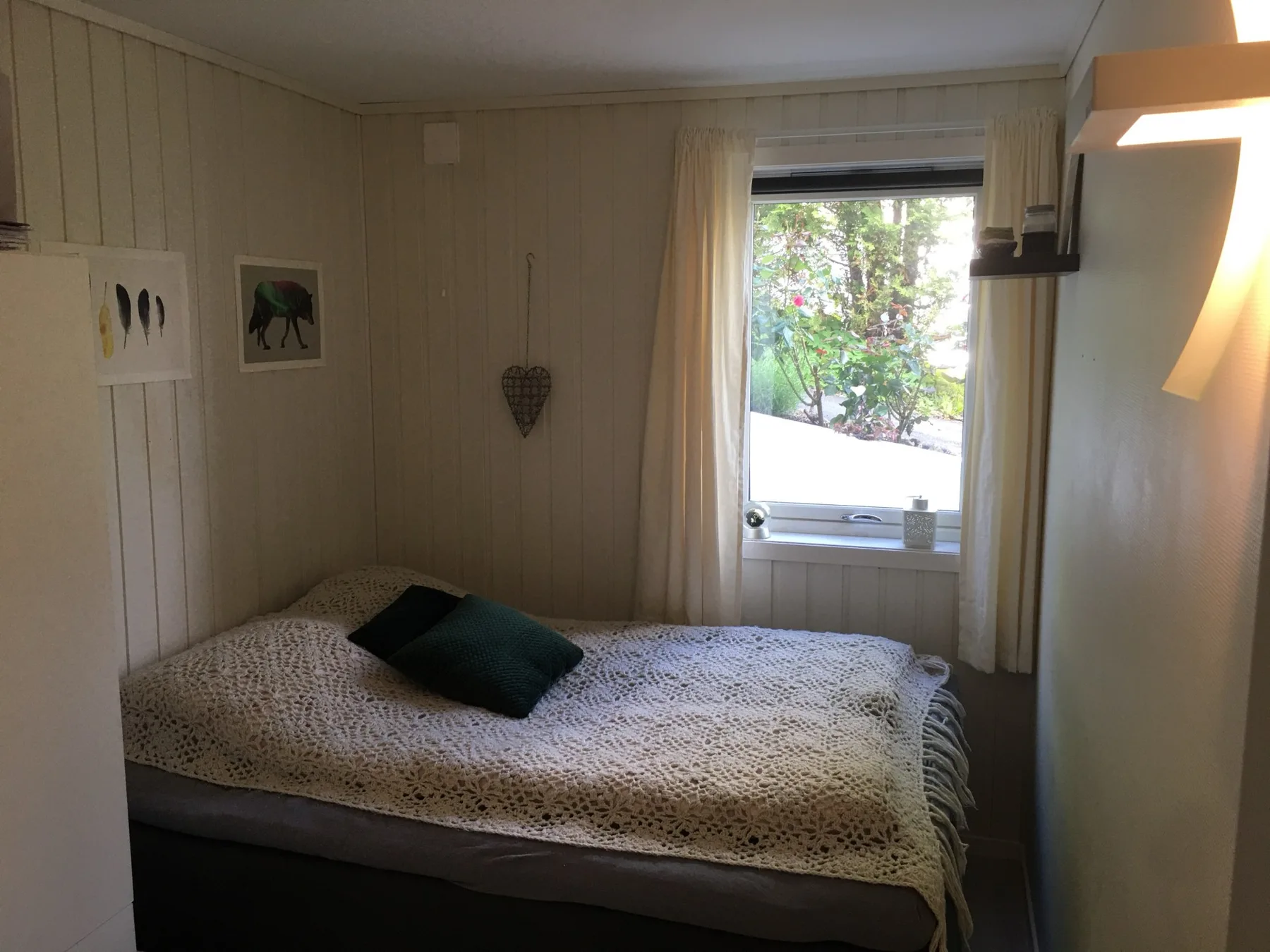 Un dormitorio con una cama bajo una ventana que da a la vegetación.