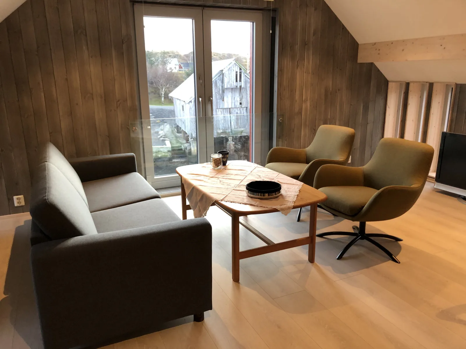 Sala de estar revestida de madera con sofá, sillones y mesa de centro.