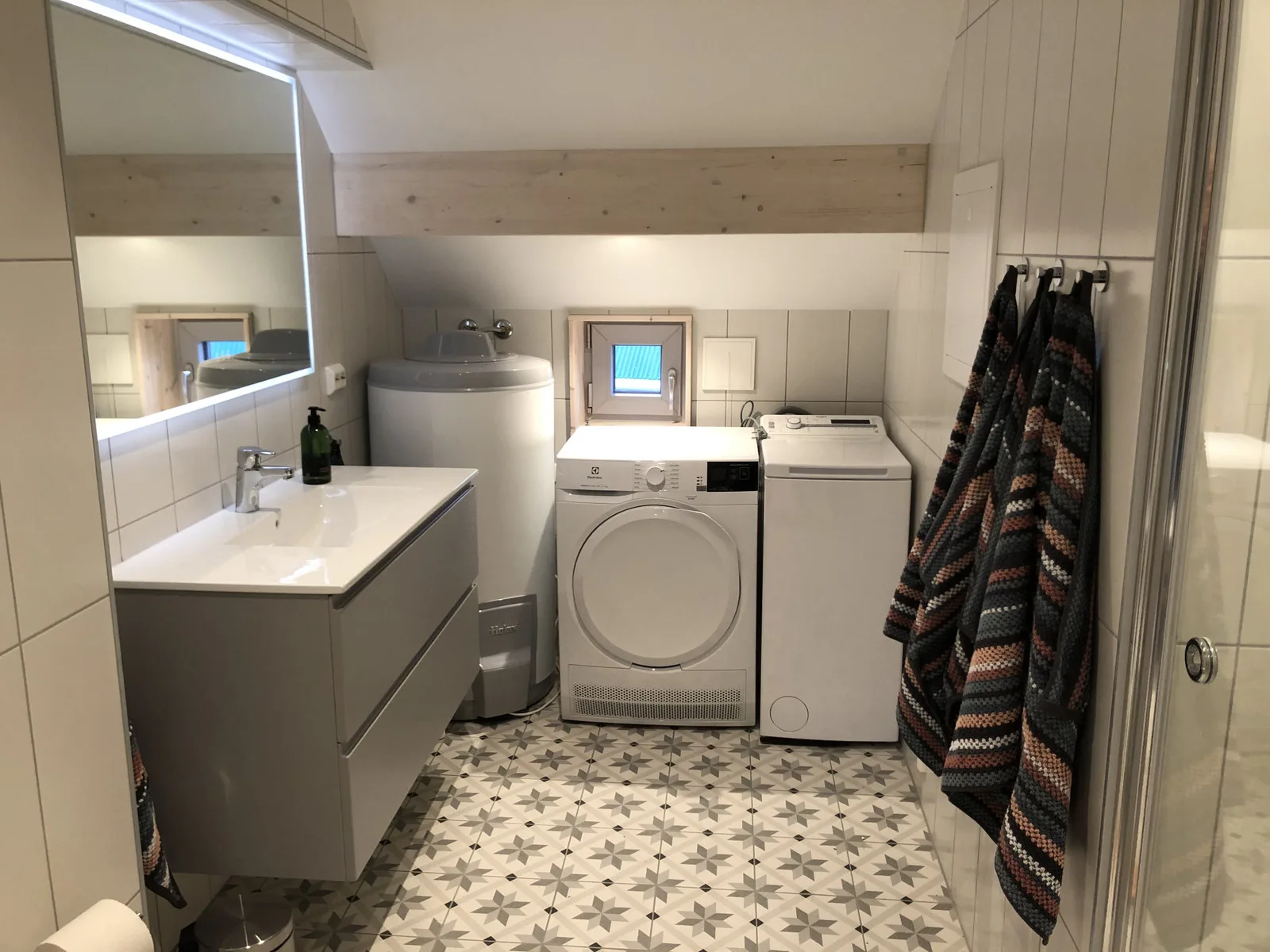 Un cuarto de lavandería con lavadora, lavabo y toallas colgadas.