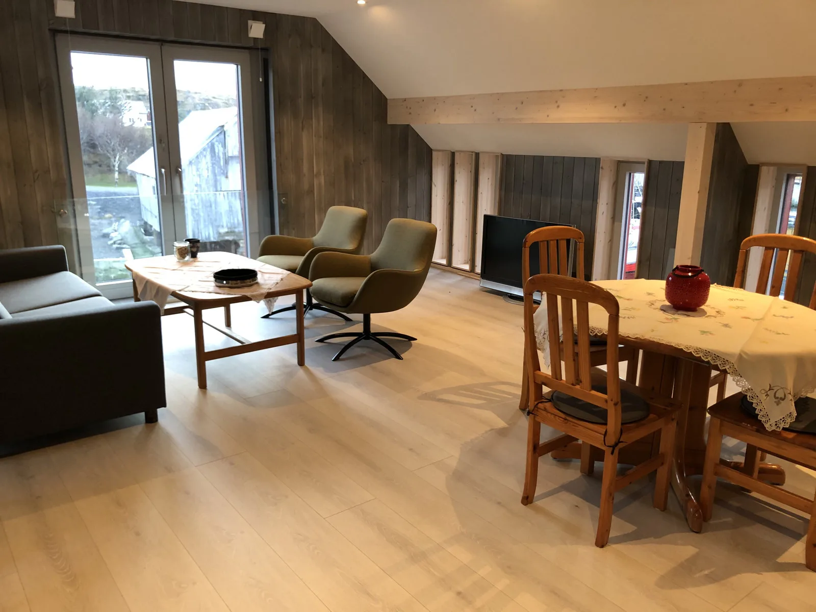 Una sala de estar y comedor con asientos, una mesa y ventanales.