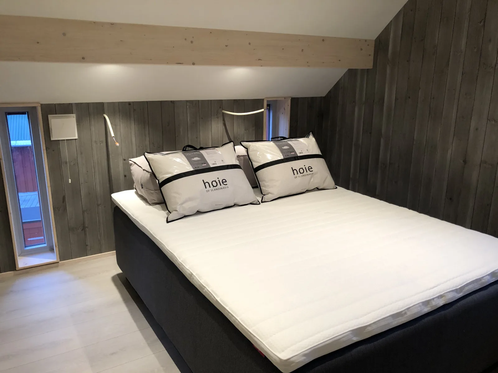Un dormitorio con una cama grande y almohadas bajo un techo inclinado.