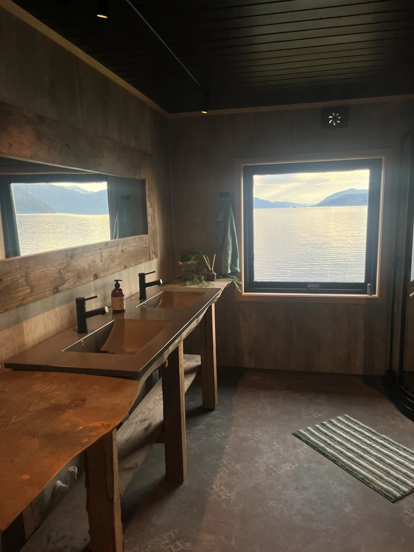Un baño con un tocador largo y una ventana grande con vistas al agua.